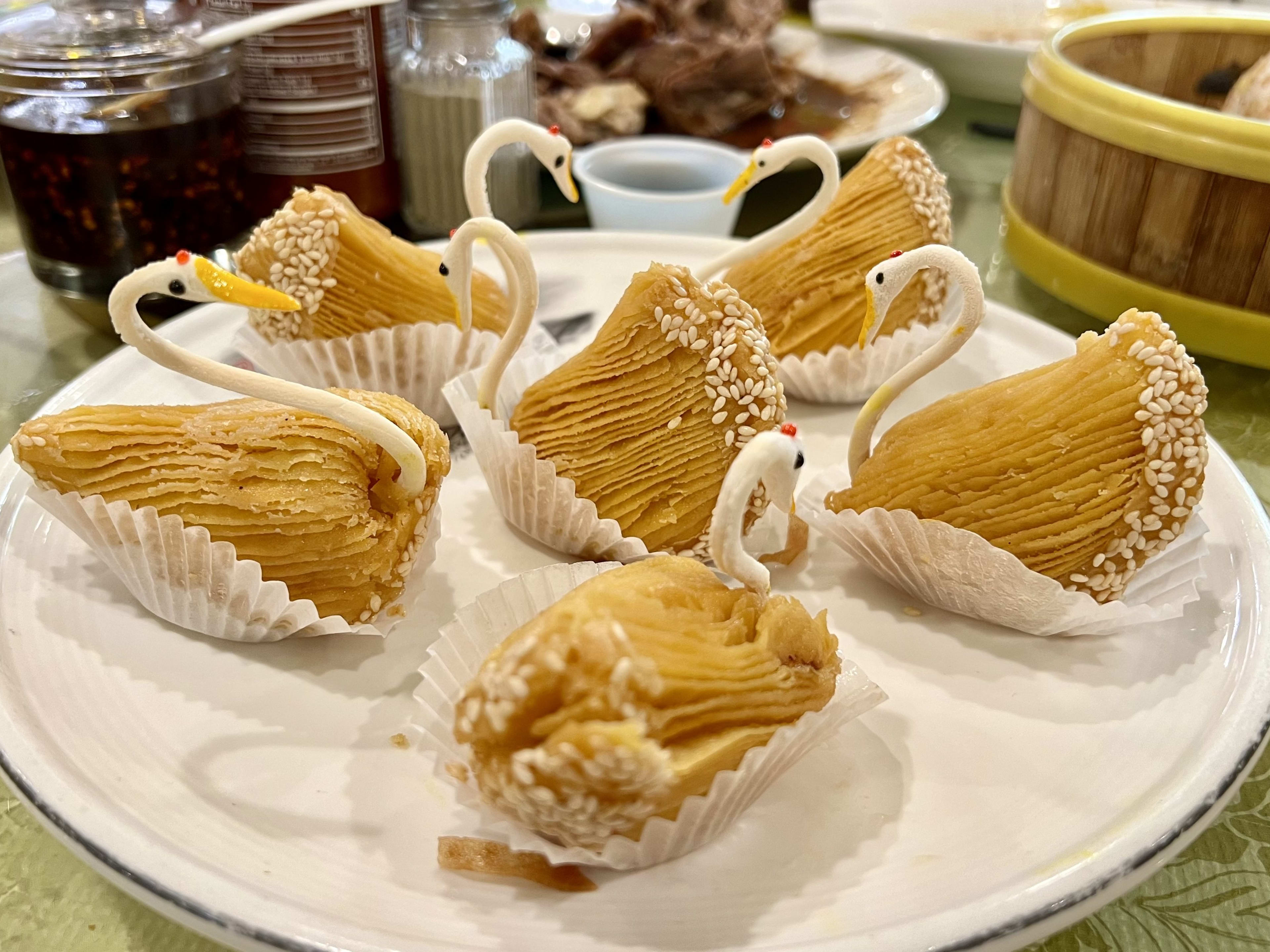 Pastries shaped like swans on a plate.