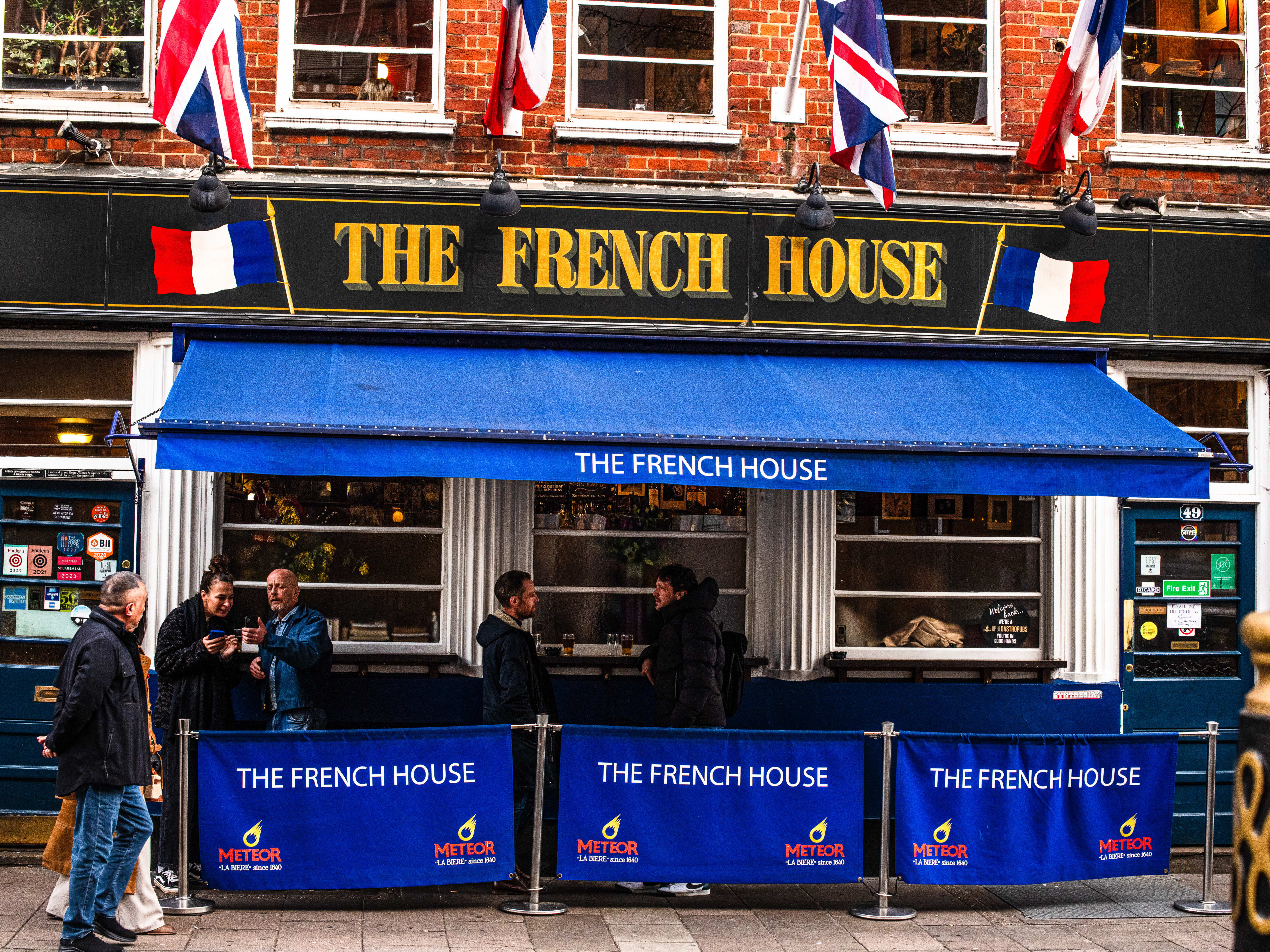 The exterior of The French House with friends drinking and smoking outside.