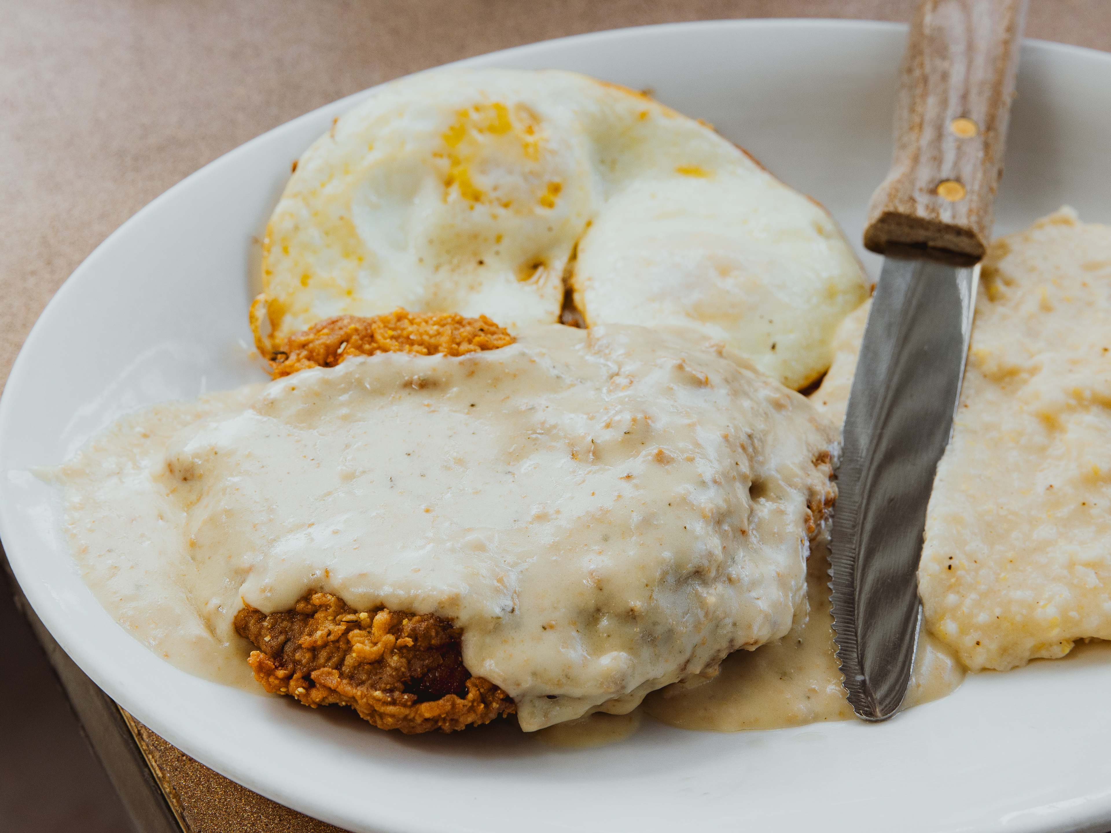 chicken fried steak with grits and fried eggs