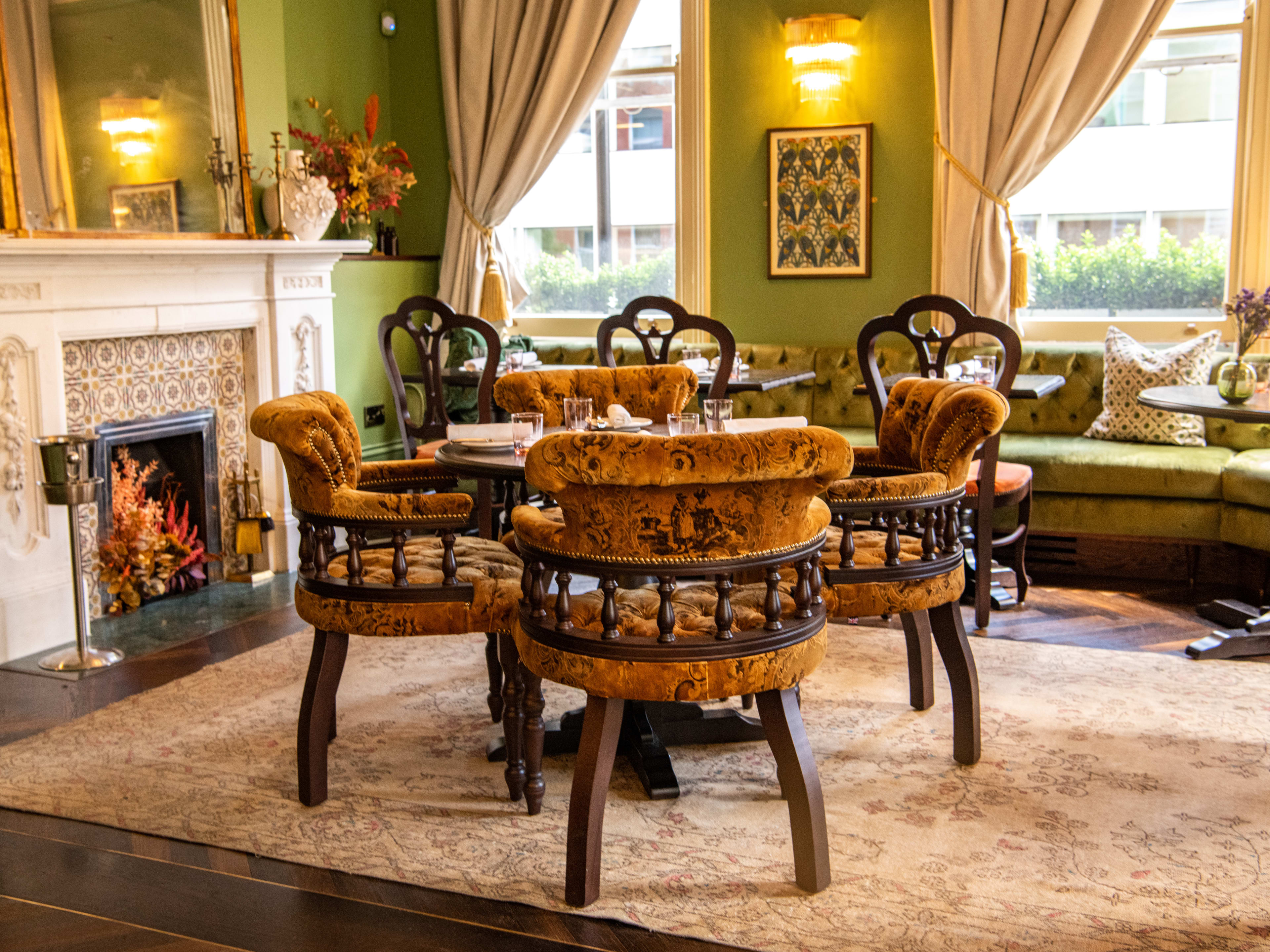 The green and gold accented dining room at The George. A fireplace roars.