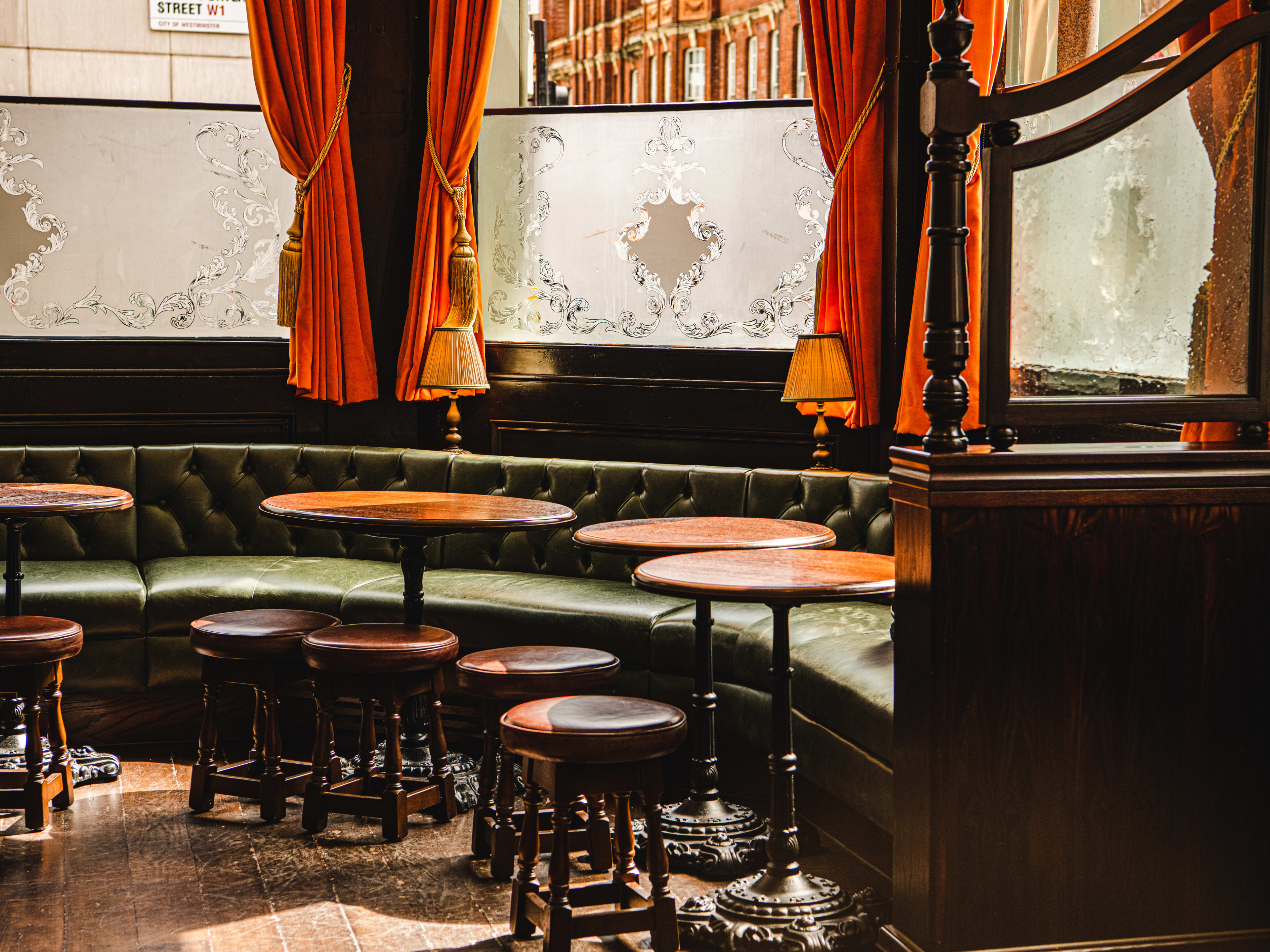 The green banquette seating area at The George. Orange curtains hang on the windows.