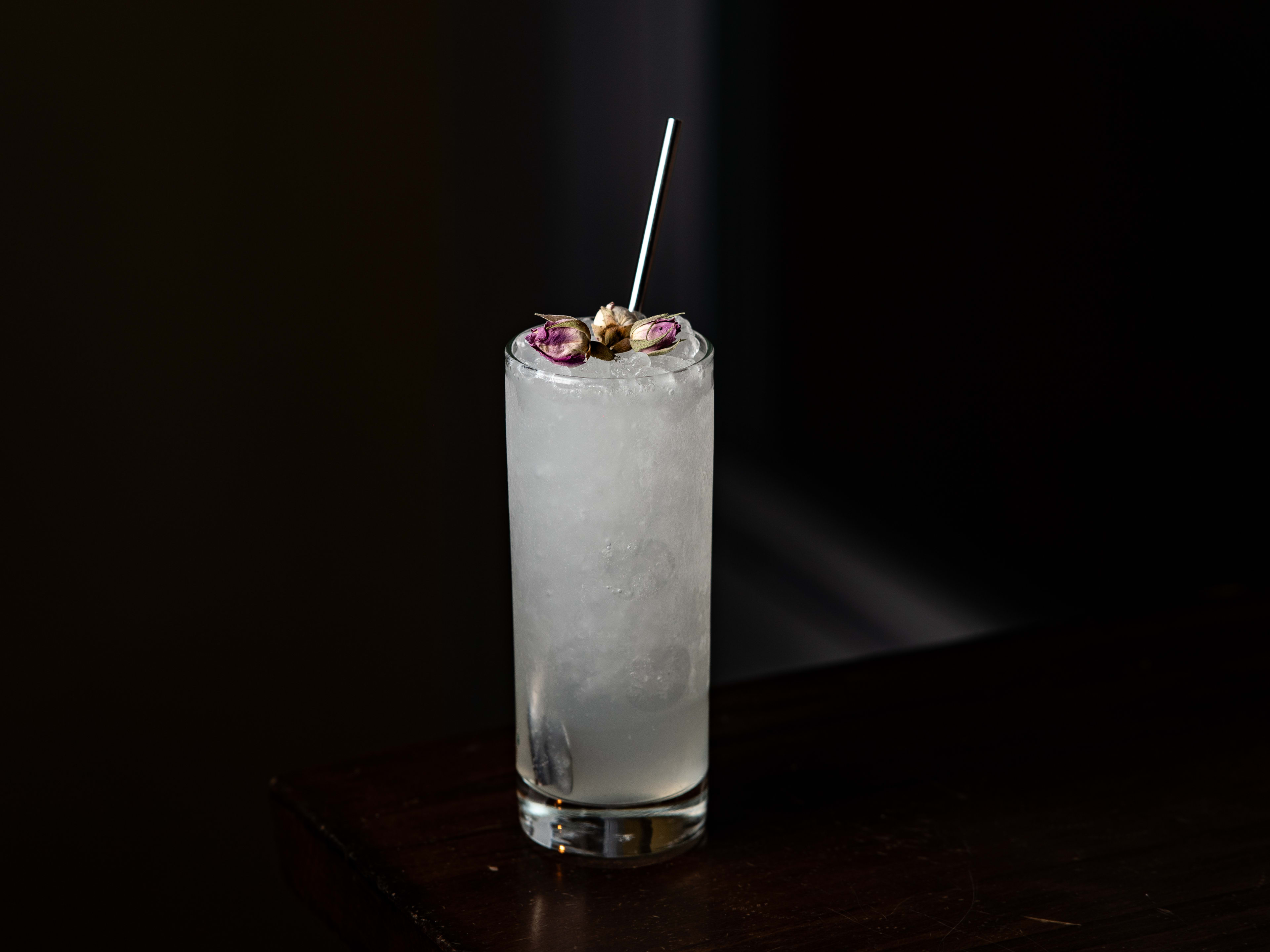 transparent cocktail in tall glass with dried roses