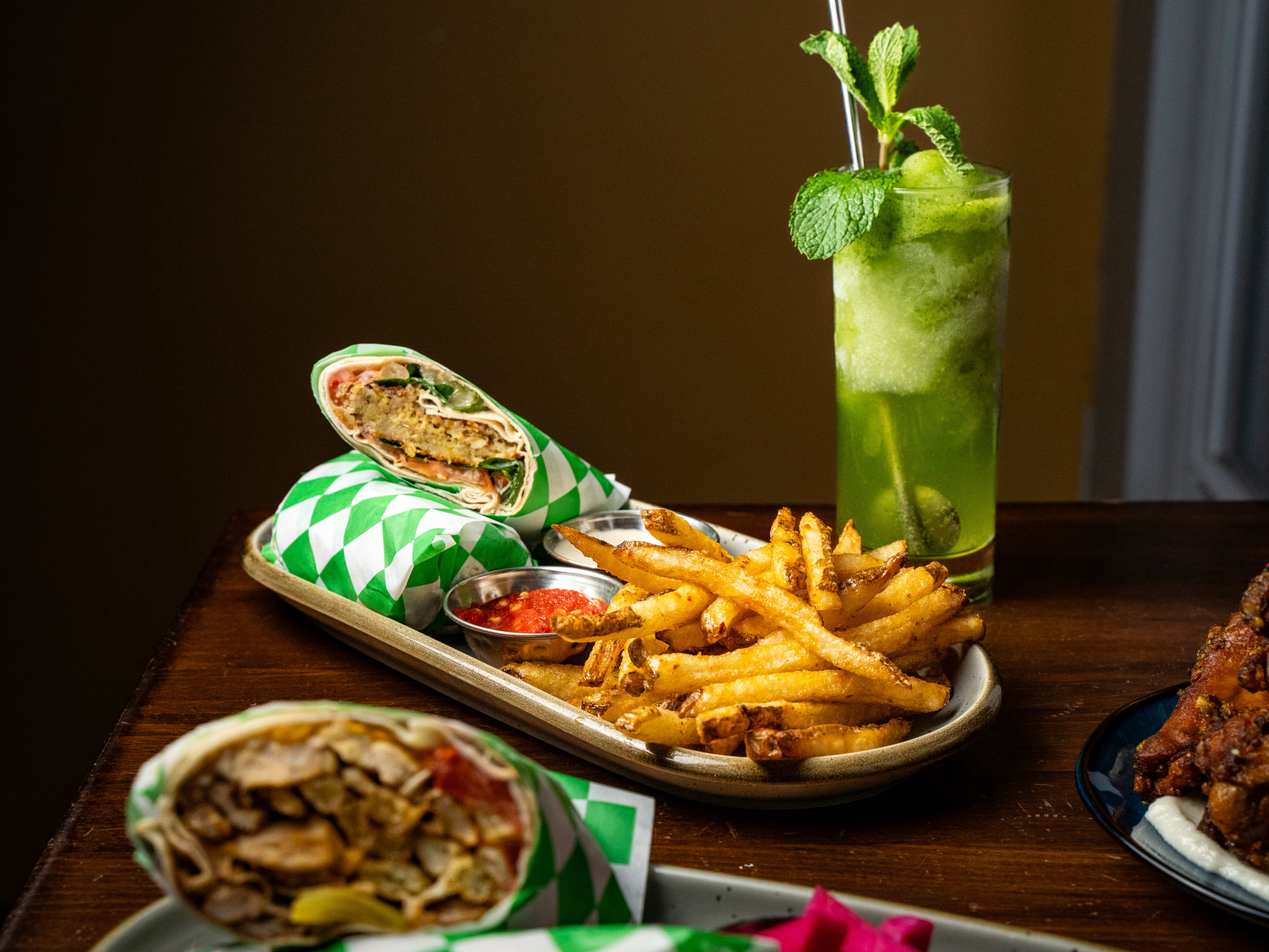 Wrap in patterned paper served with fries and surrounded by colorful cocktails.