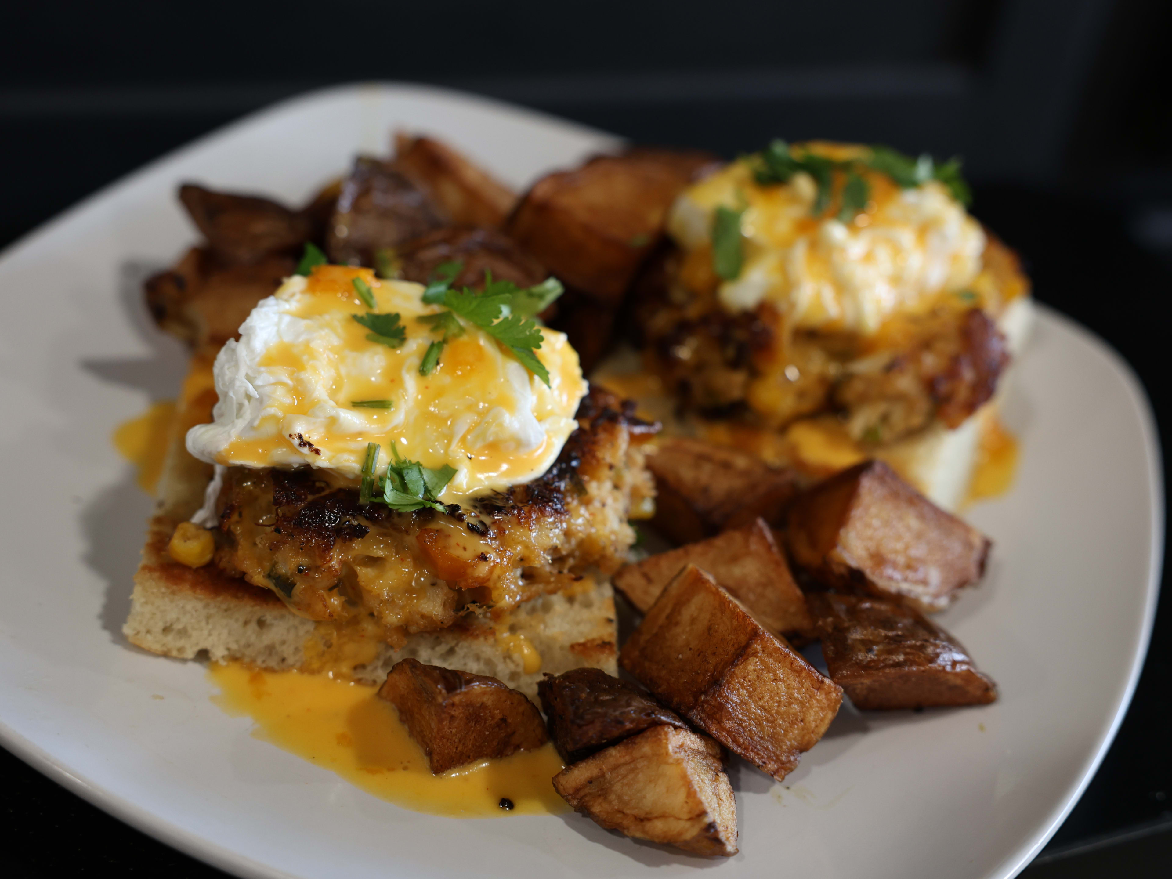 Plate of crab benedict with roasted potatoes on the side