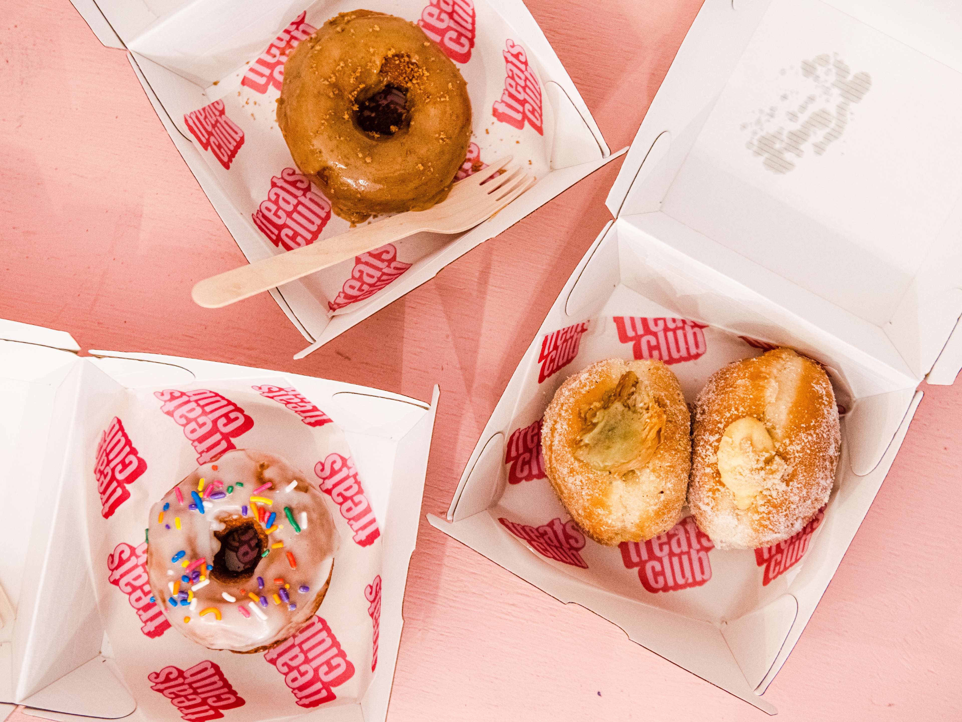 A spread of doughnuts in takeaway containers from The Treats Club.