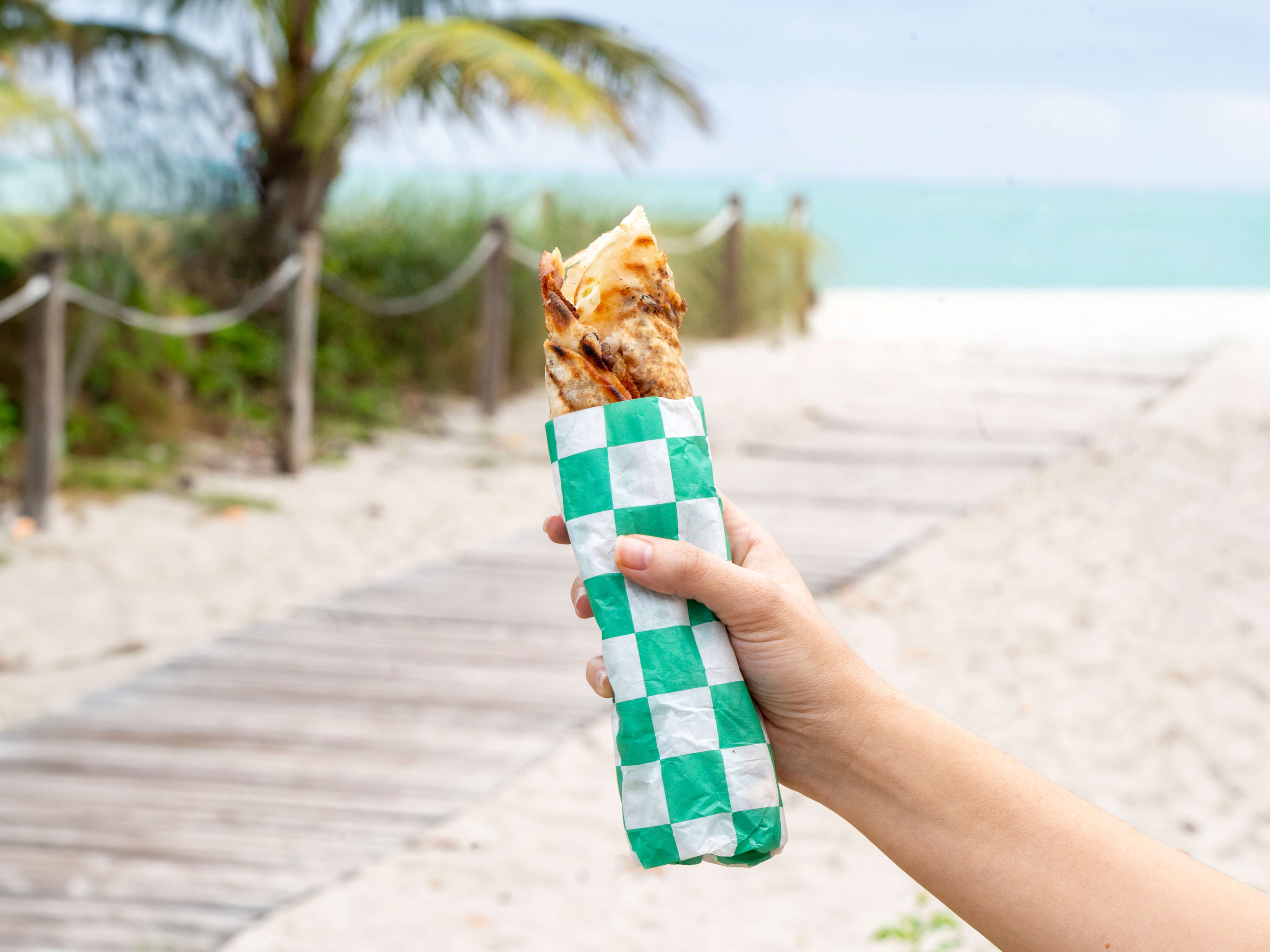 Hand holding wrap up to sandy beach background