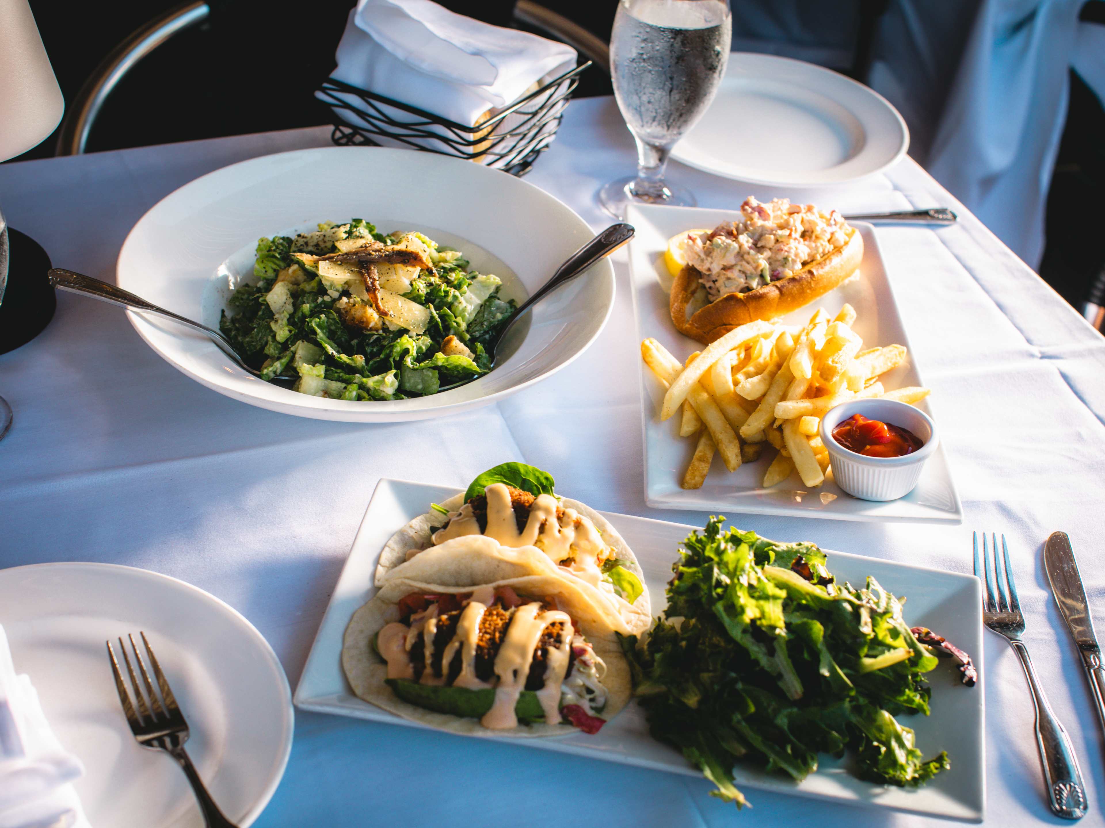 An overhead shot of various dinner dishes on a white table cloth