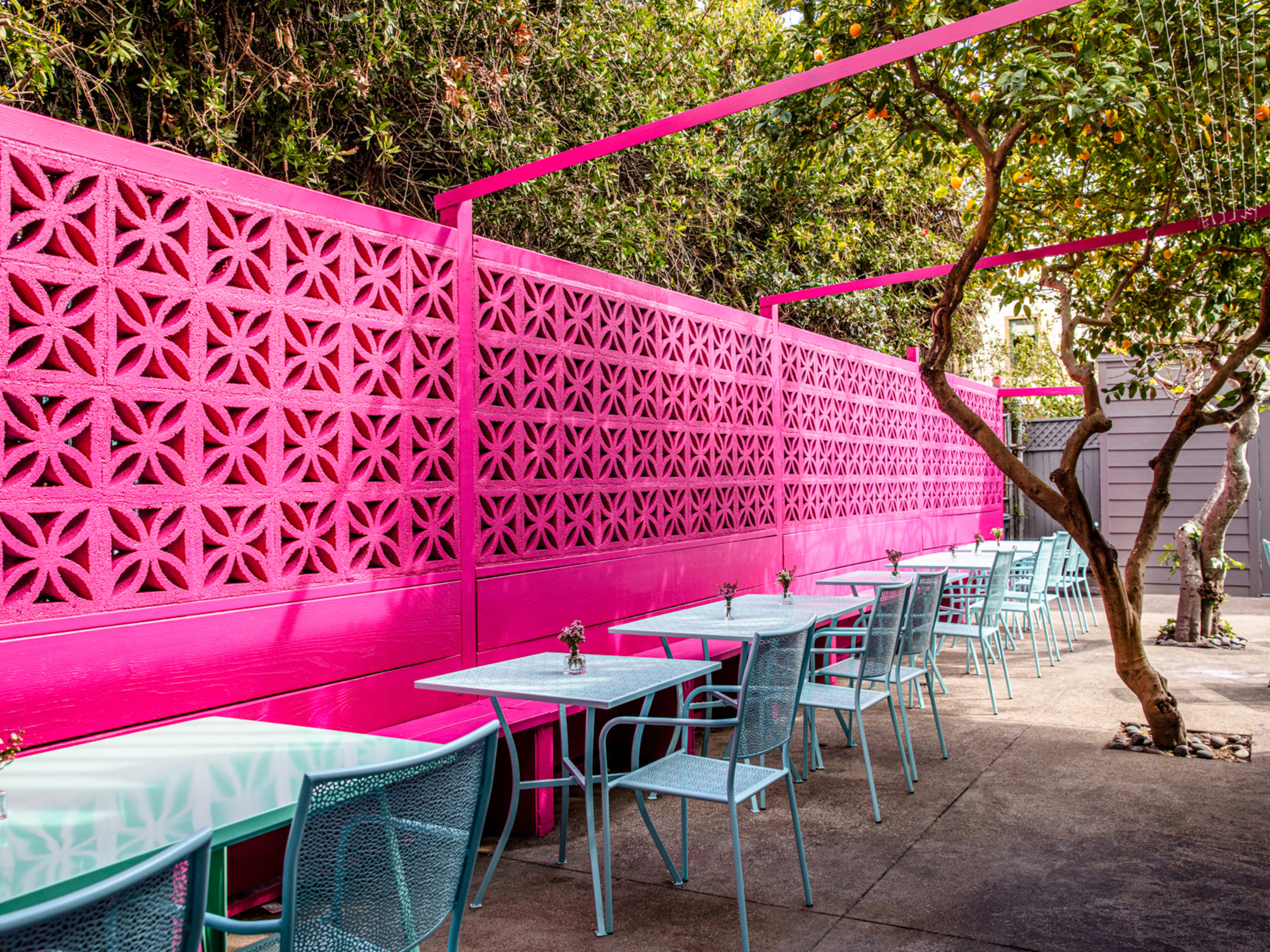 back patio with colorful walls and tables and live trees