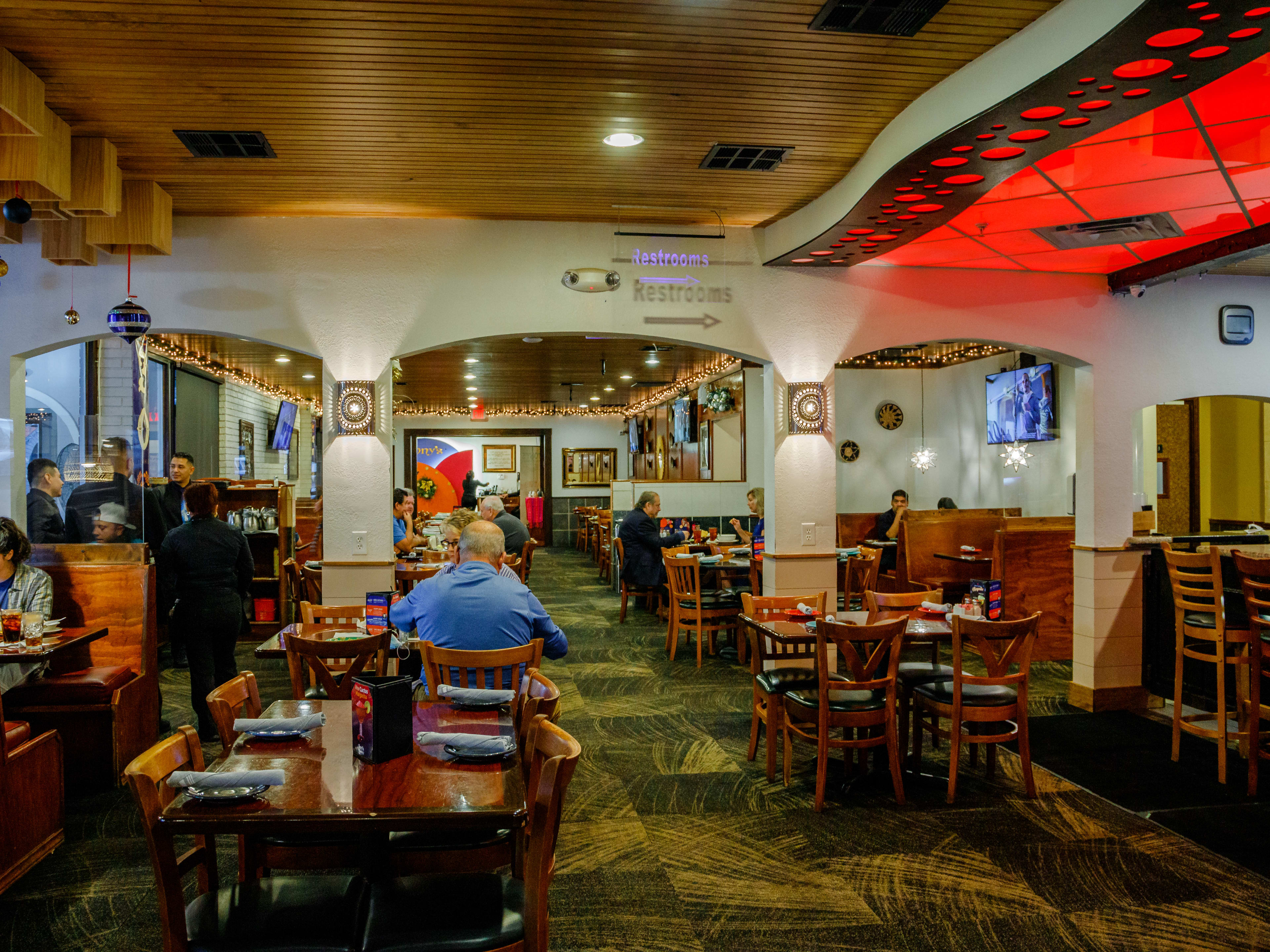 People dine inside Tony's Mexican Restaurant. A red glass light covers the ceiling near the bar.