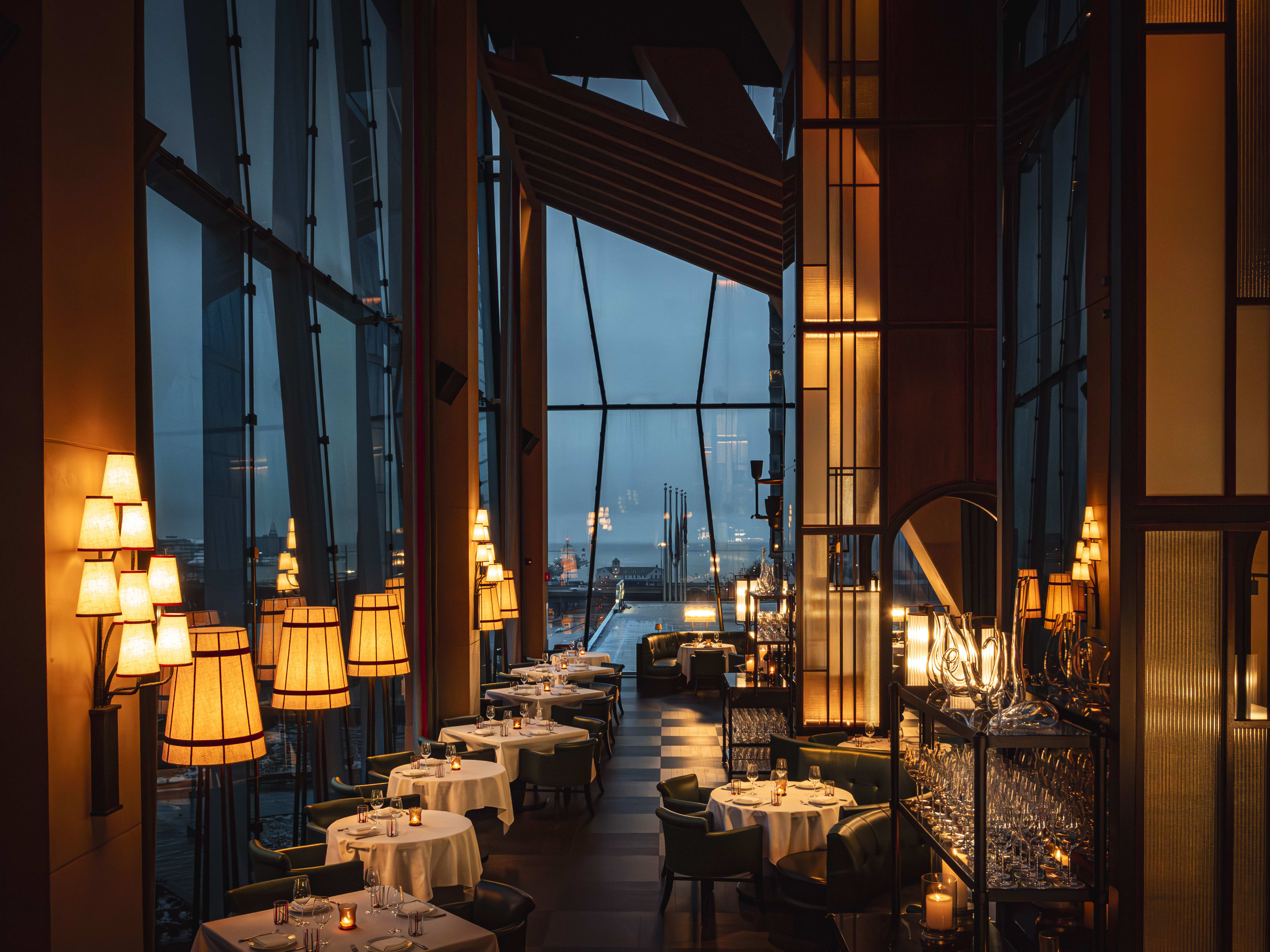 A dimly lit dining room with white tablecloths and high ceilings.