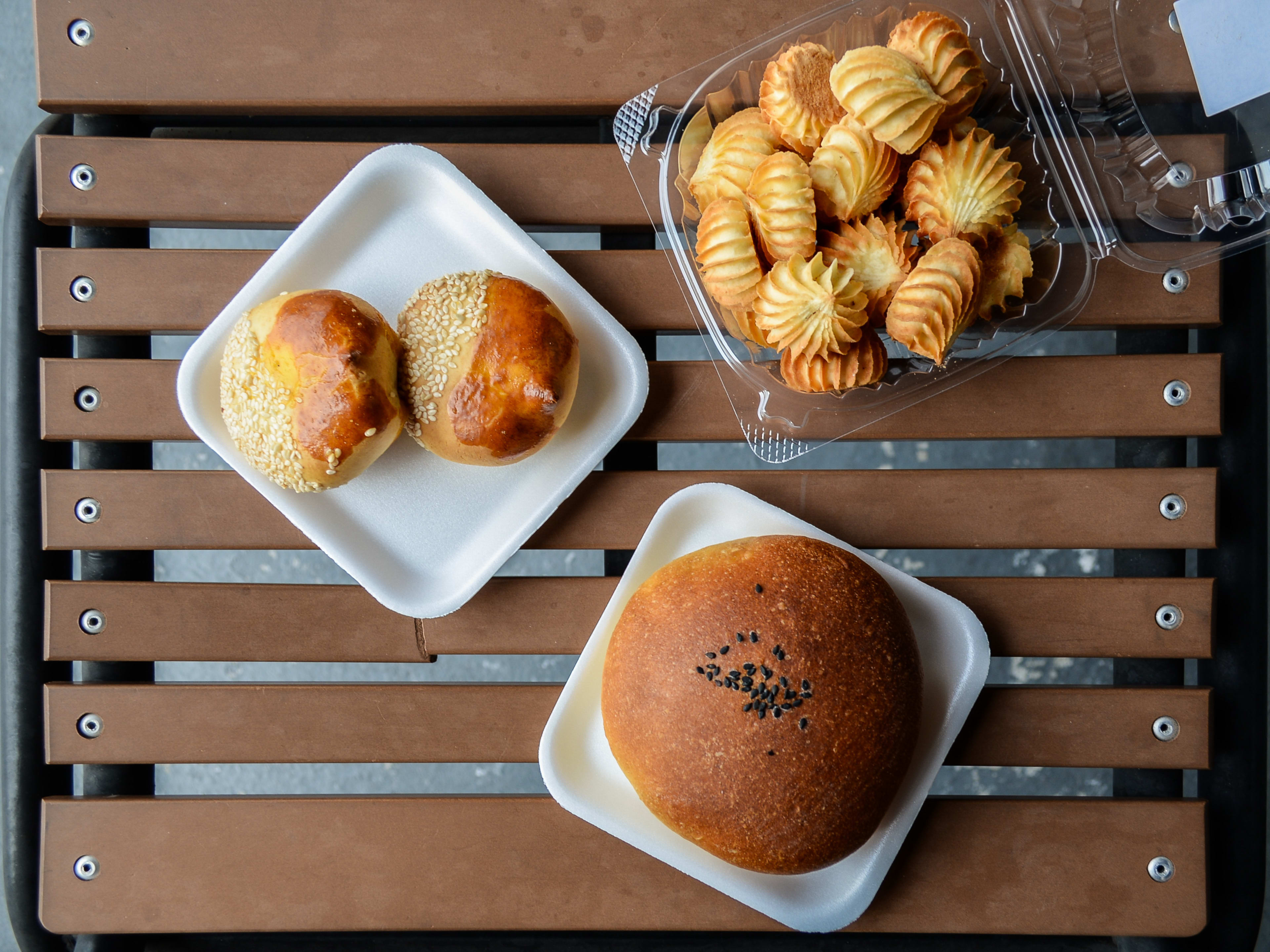 Outdoor table with plates of pastries such as cookies and buns.