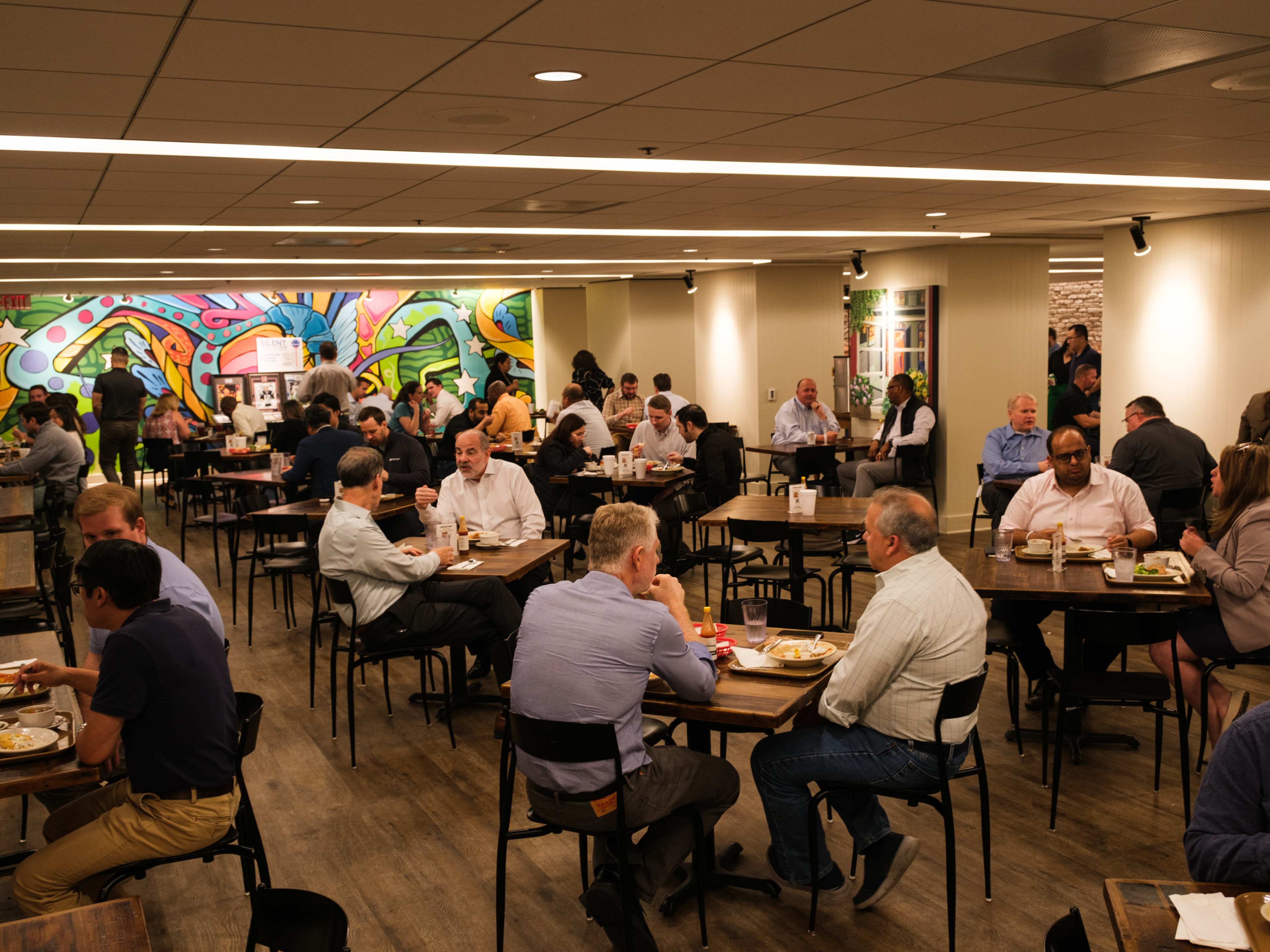 People dining at tables inside Treebeards. A colorful mural covers the back wall.