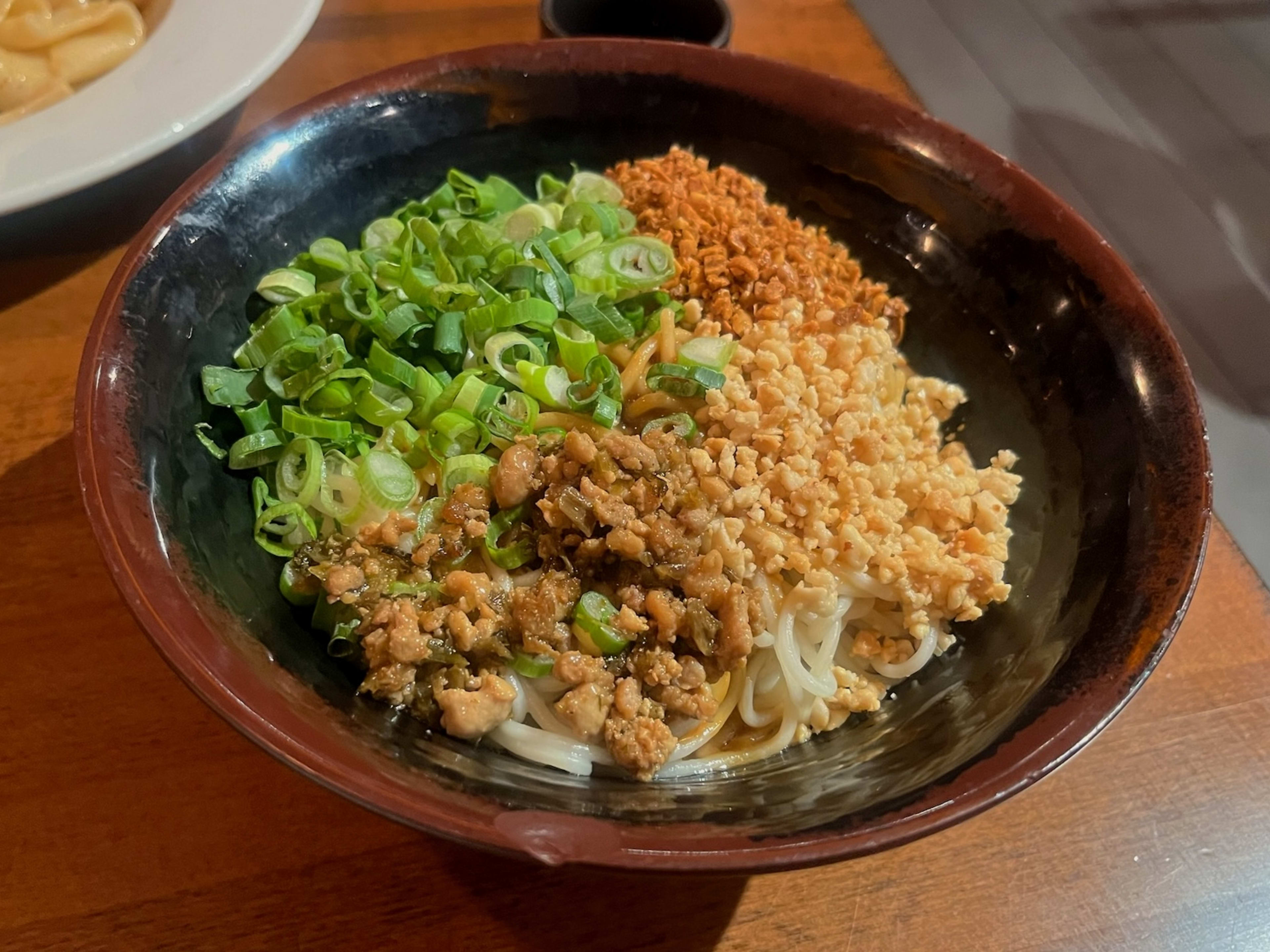 bowl of spicy dan dan noodles with green onions