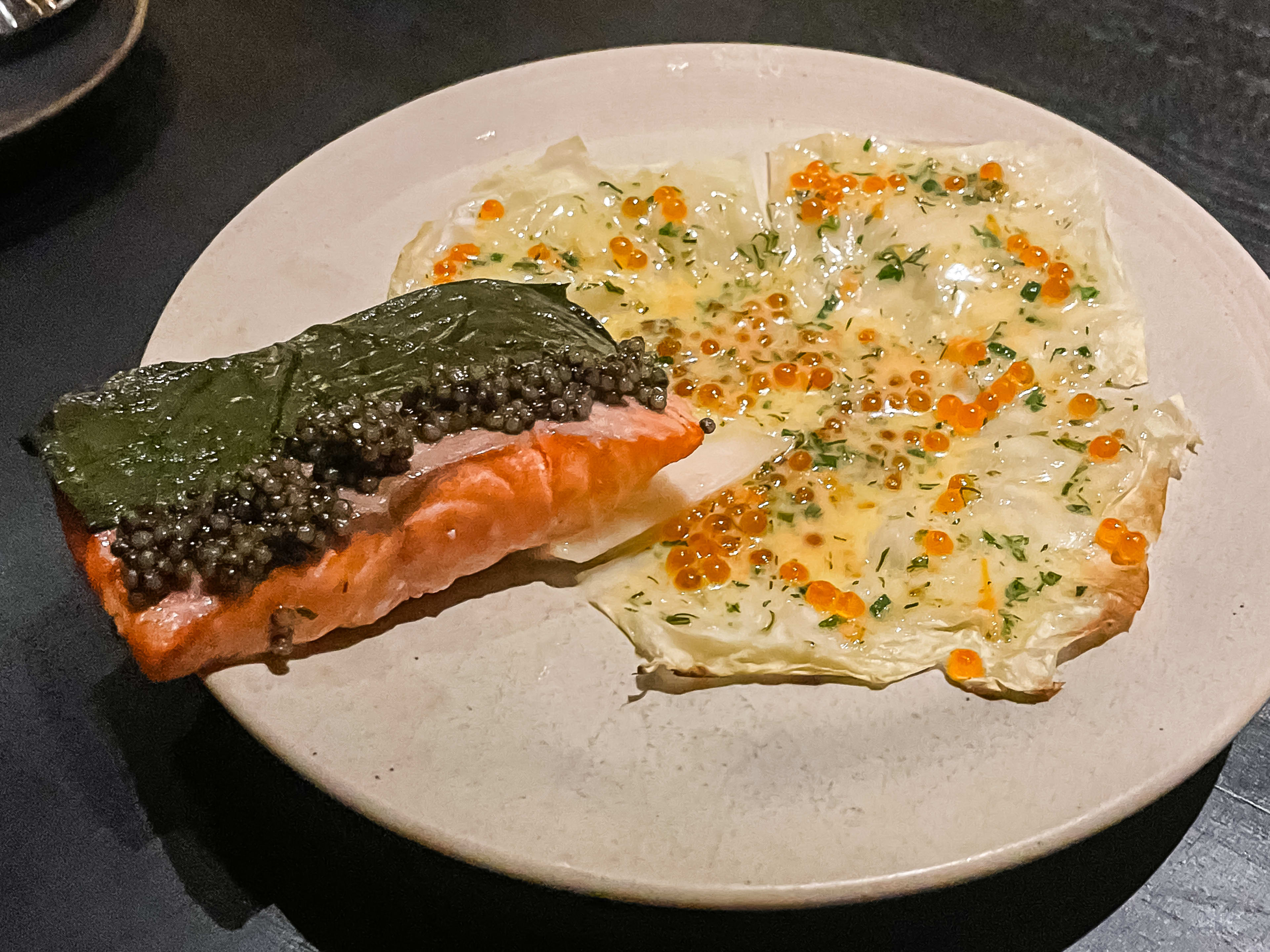 A piece of trout with cabbage on the side that's topped with trout roe.