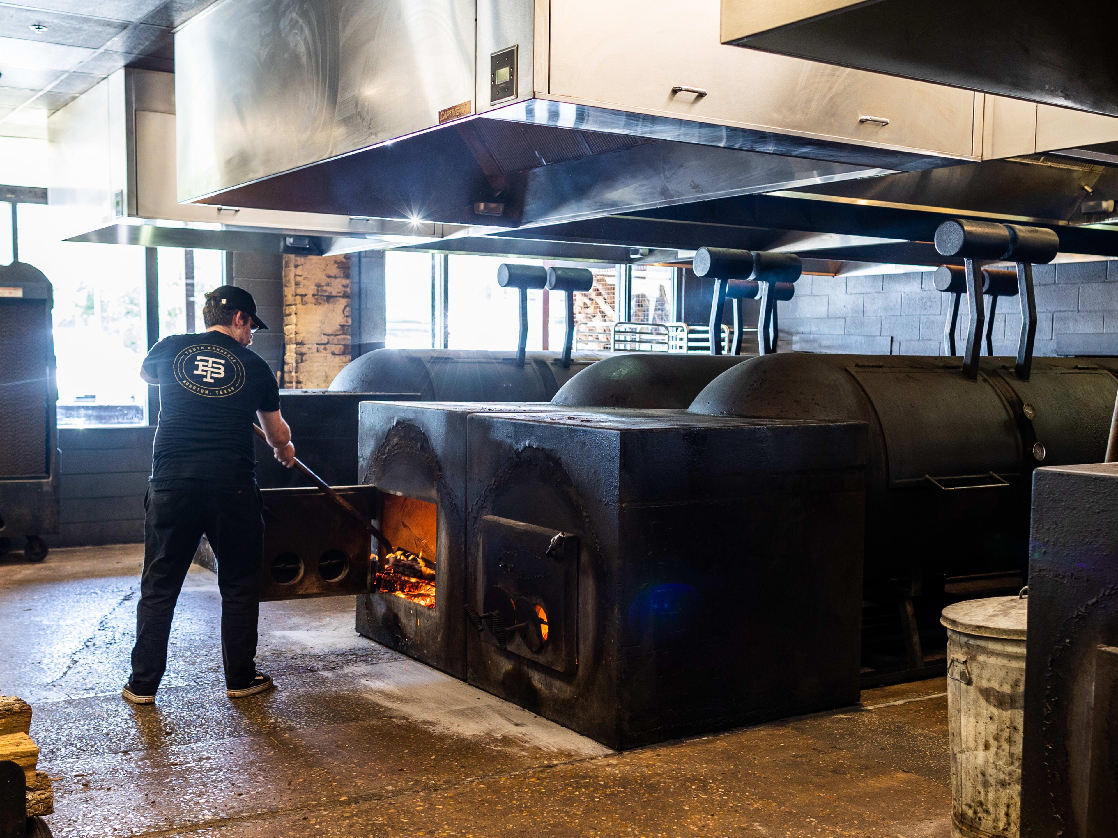 A chef stokes the fire in the grill at Truth BBQ.