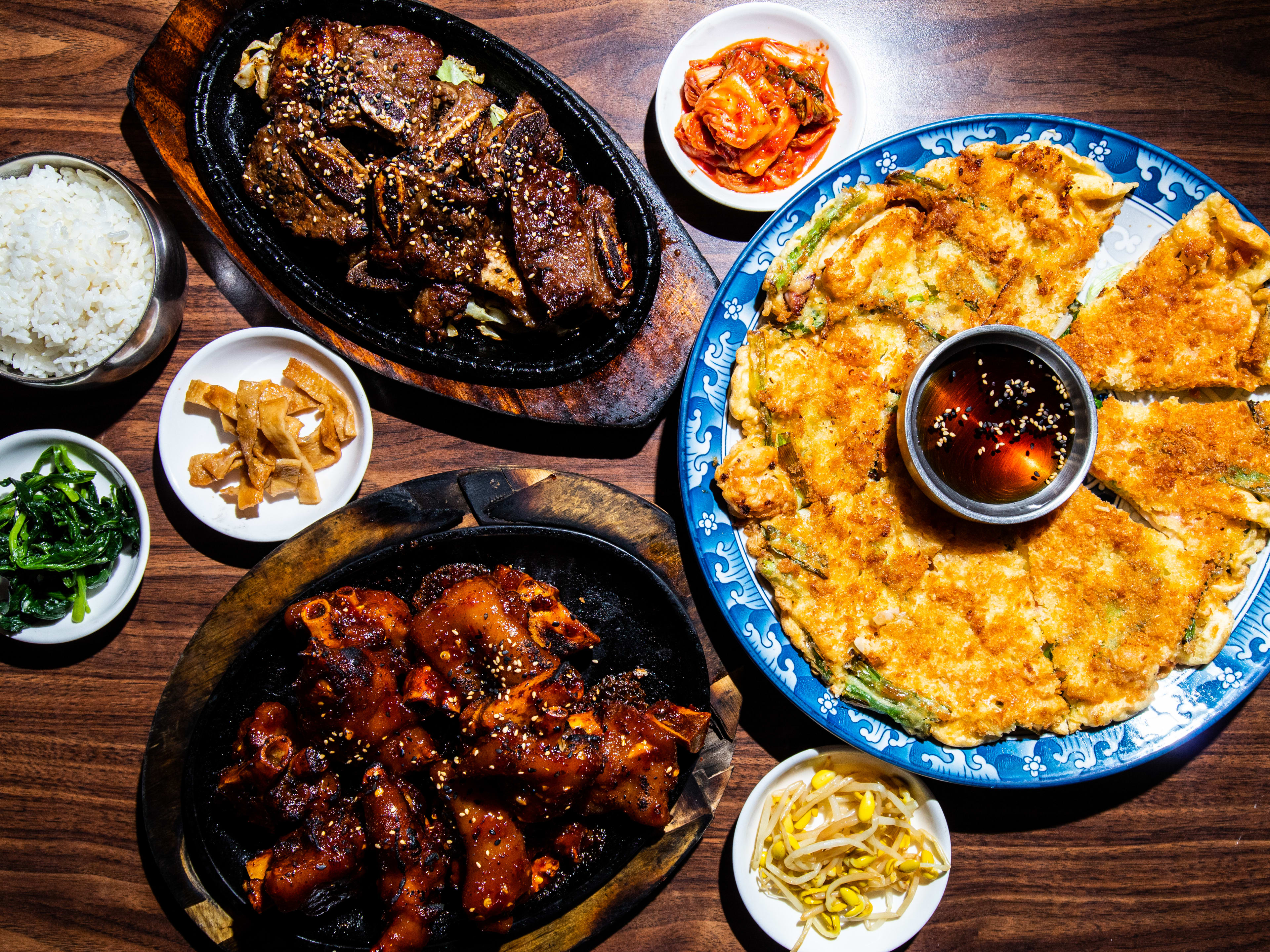 Spread of Korean dishes such as short rib, kimchi, scallion pancake with dipping sauce.