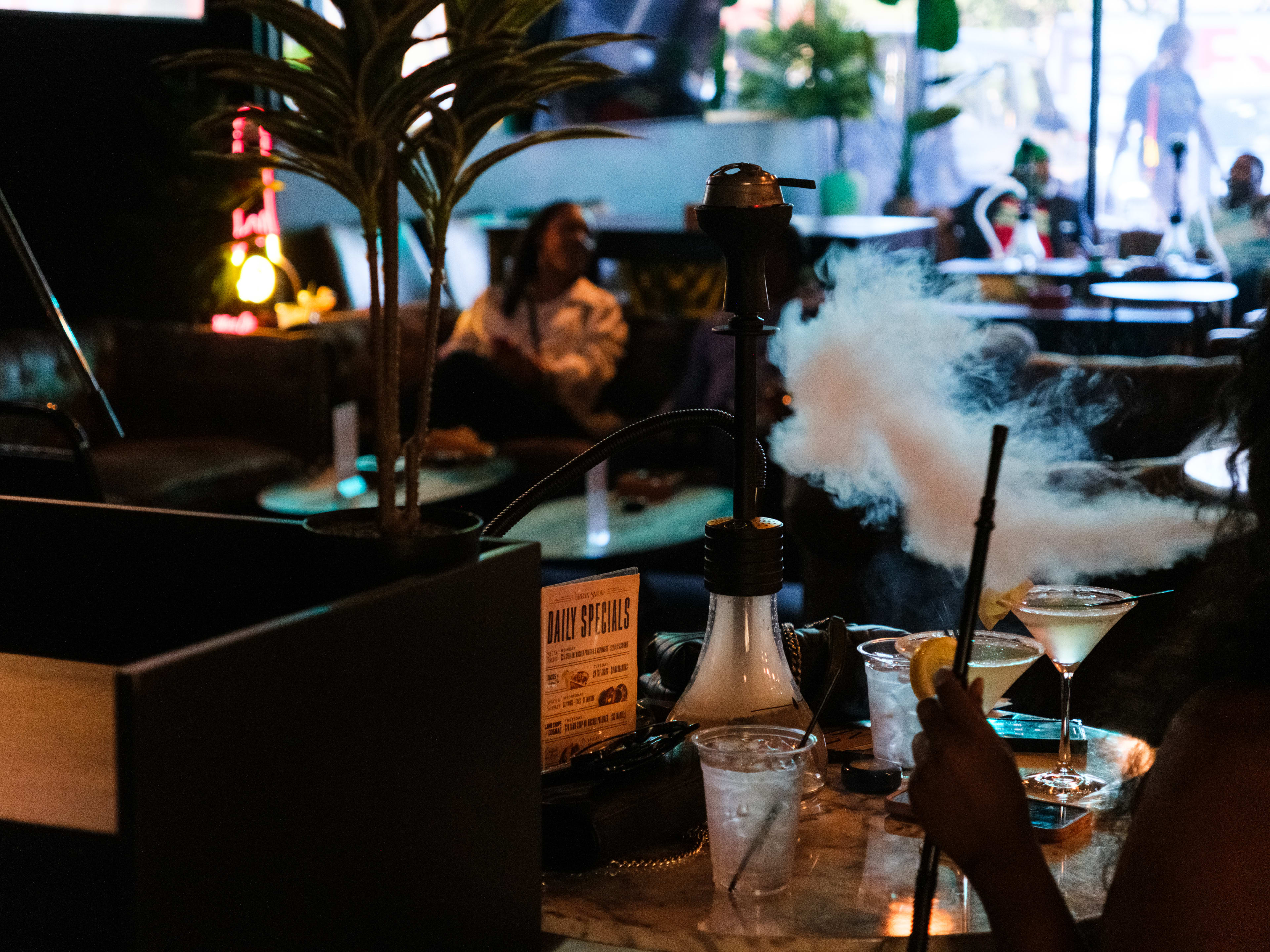 A person smoking hookah at the bar at Urban Smoke.