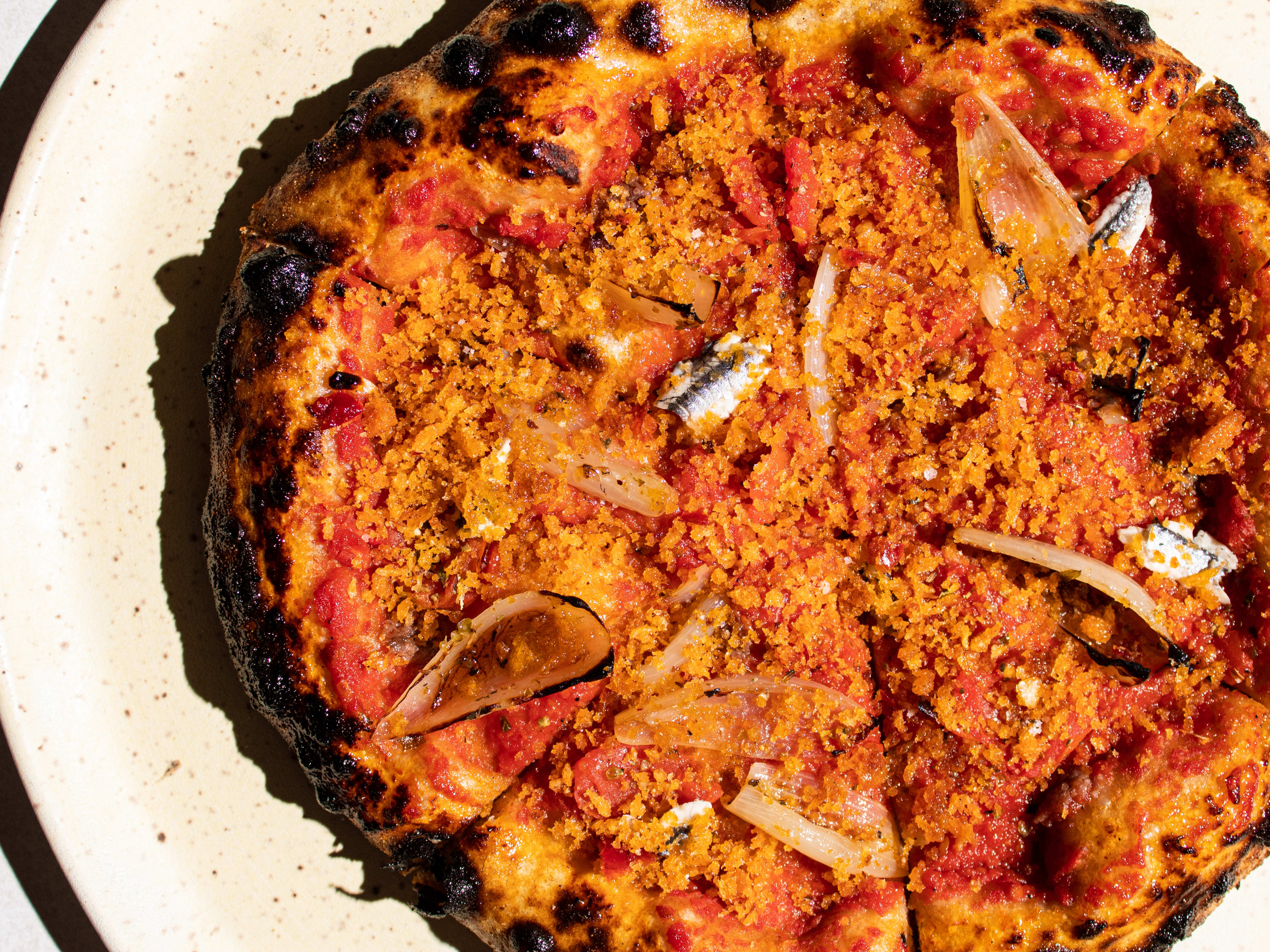 A pizza covered in breadcrumbs and anchovies.