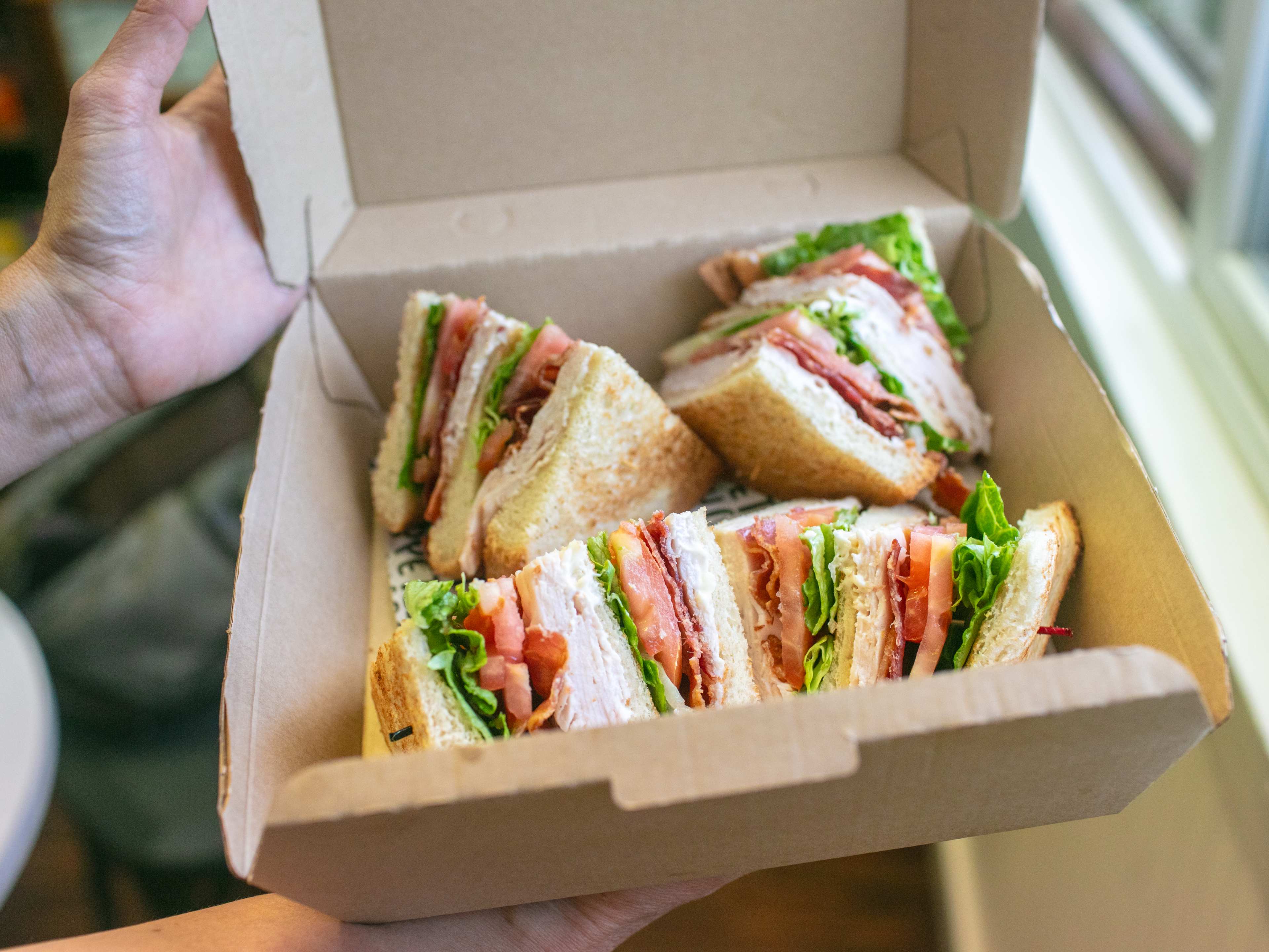 A box of turkey club sandwiches by a window