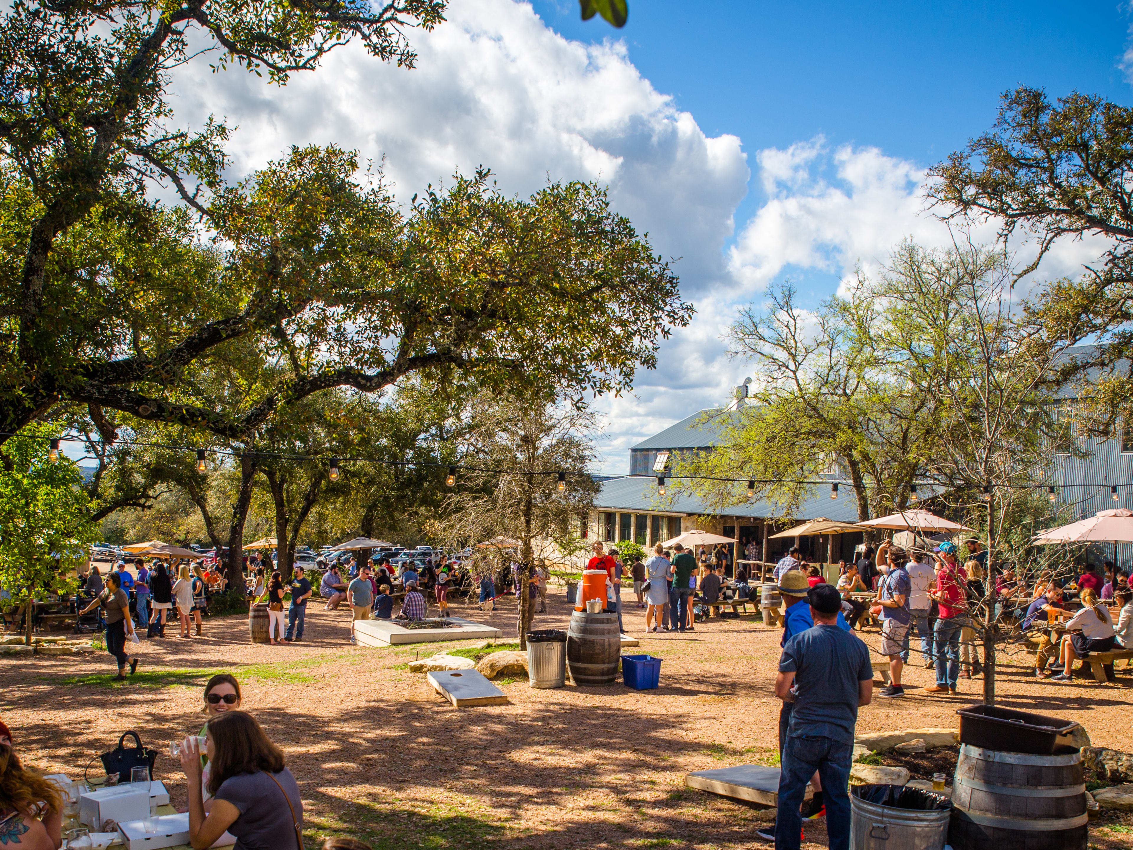 The outdoor patio area at Jester King with people sitting at picnic tables and walking around.