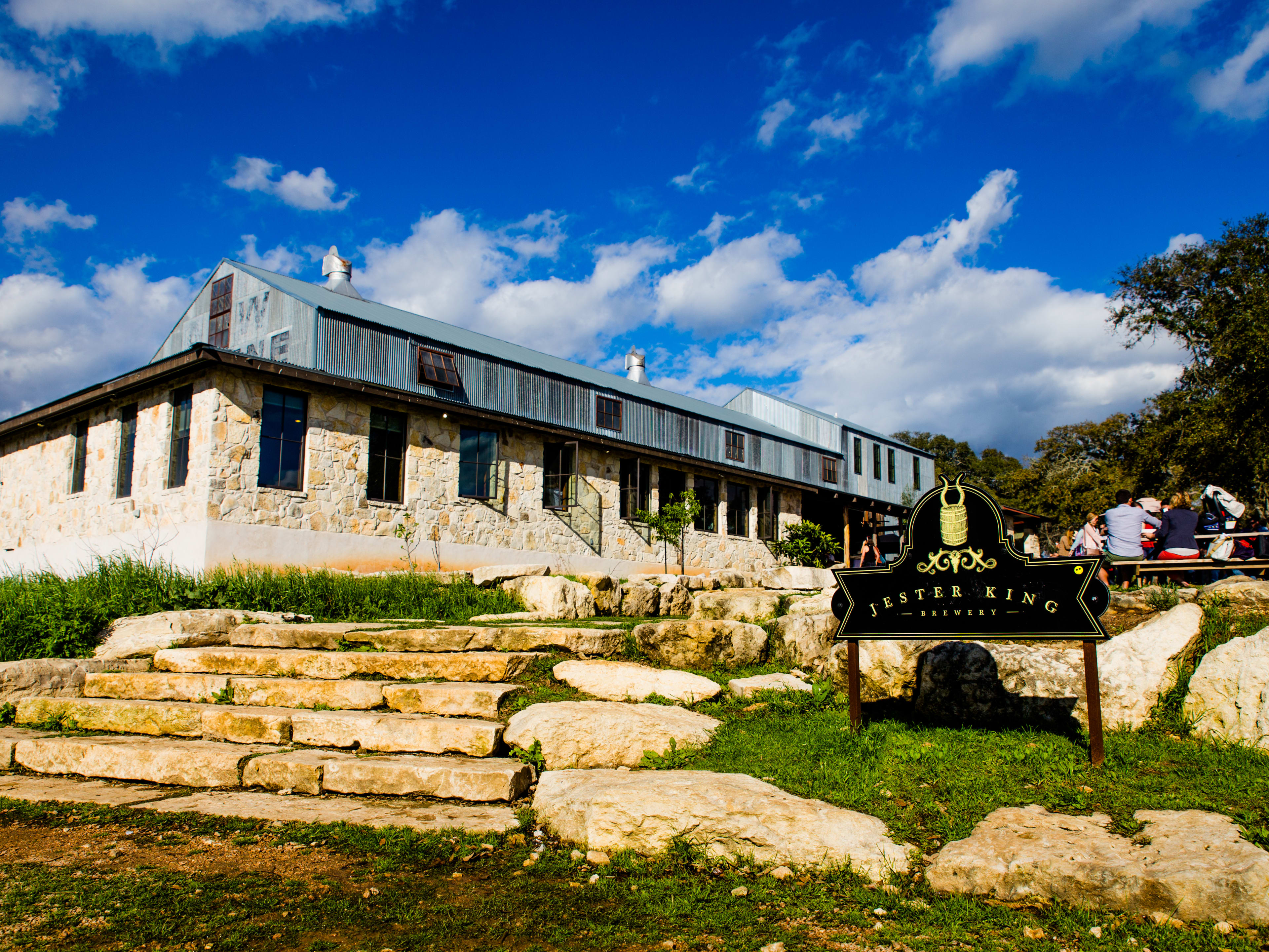 The exterior of Jester King Brewery with natural rock staircases and a rock building facade.