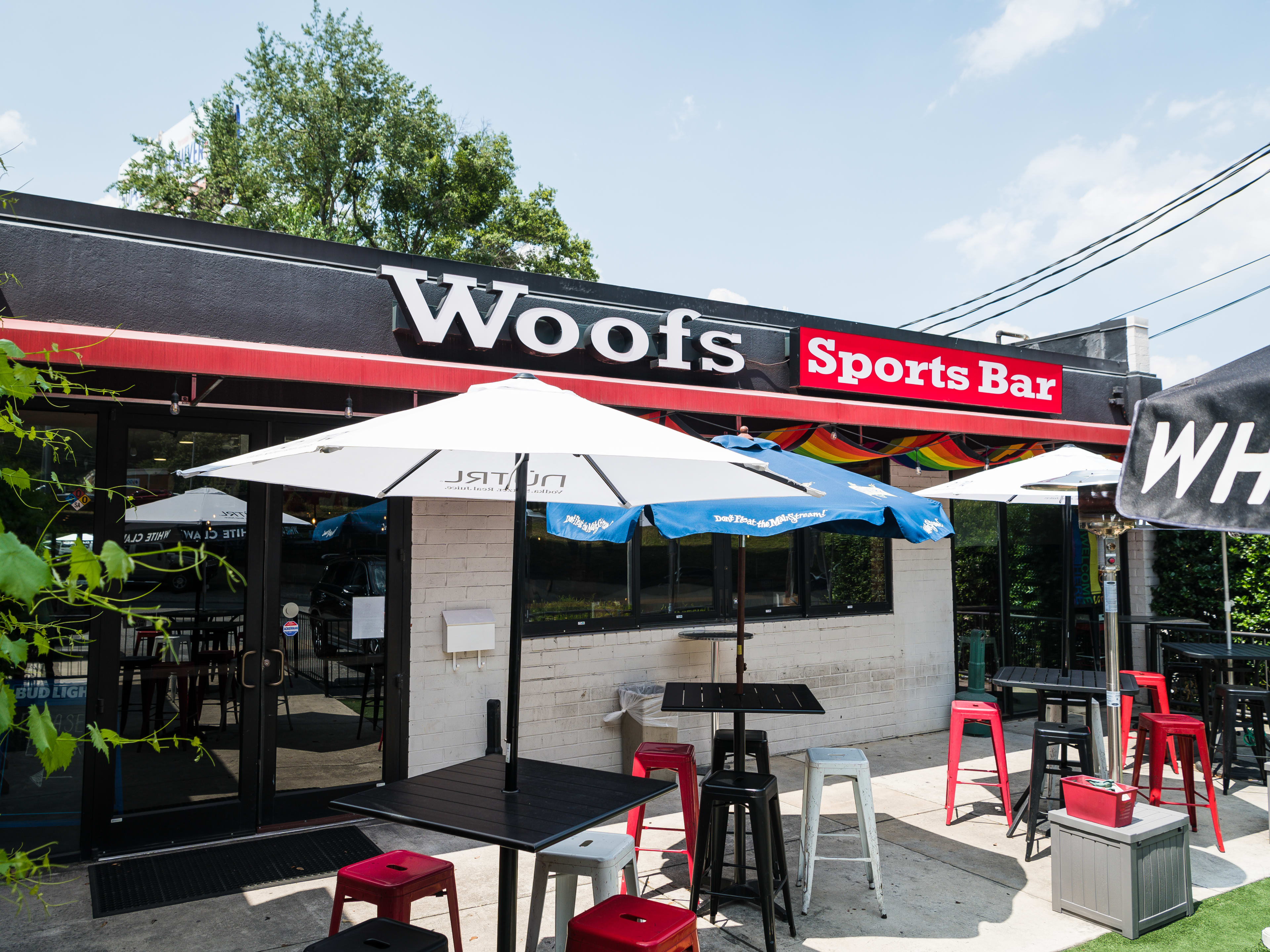 The patio of Woofs Sports Bar with tables and umbrellas.