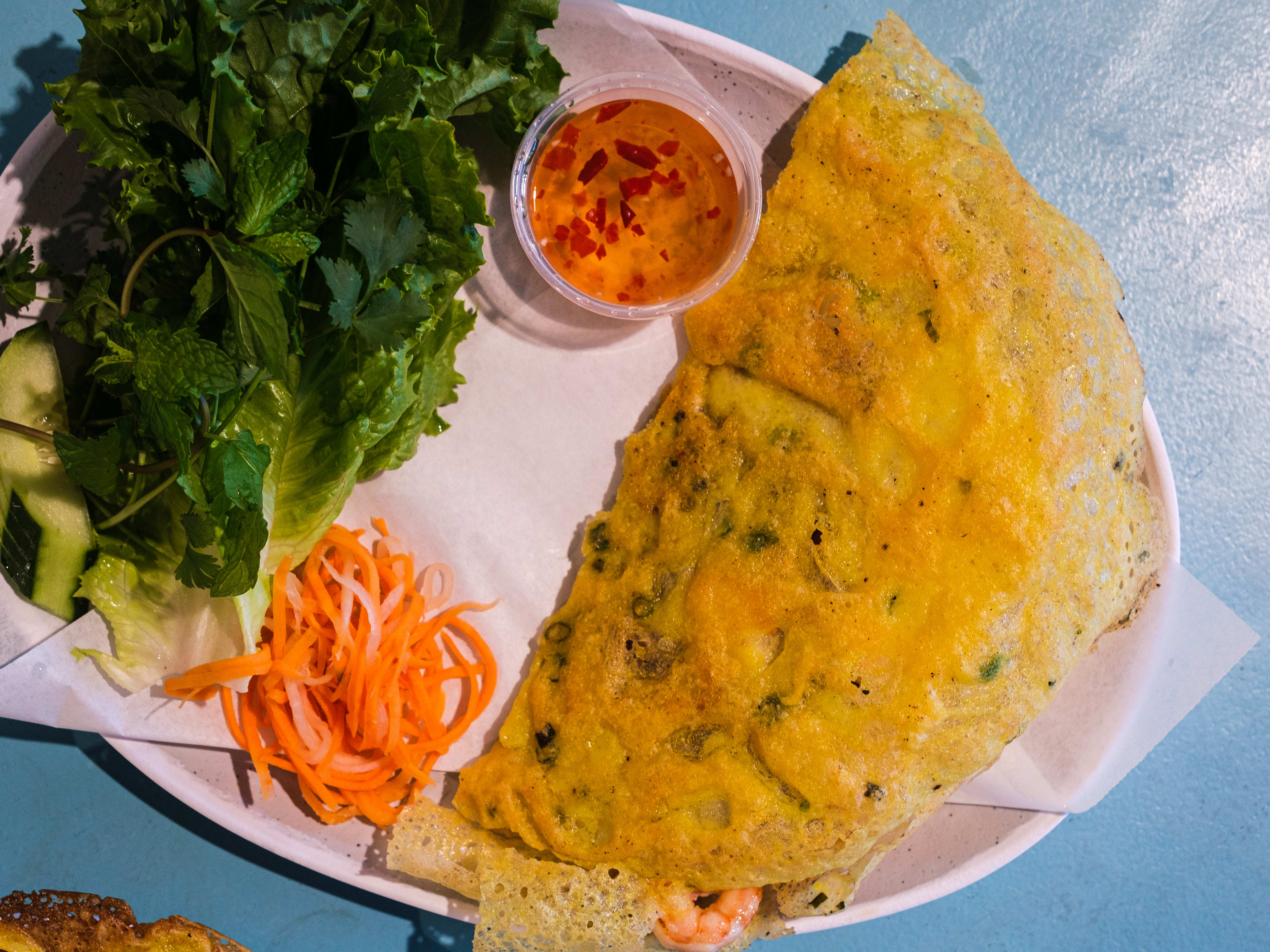 Vietnamese banh xeo crispy golden yellow crepe with side of lettuce and pickles