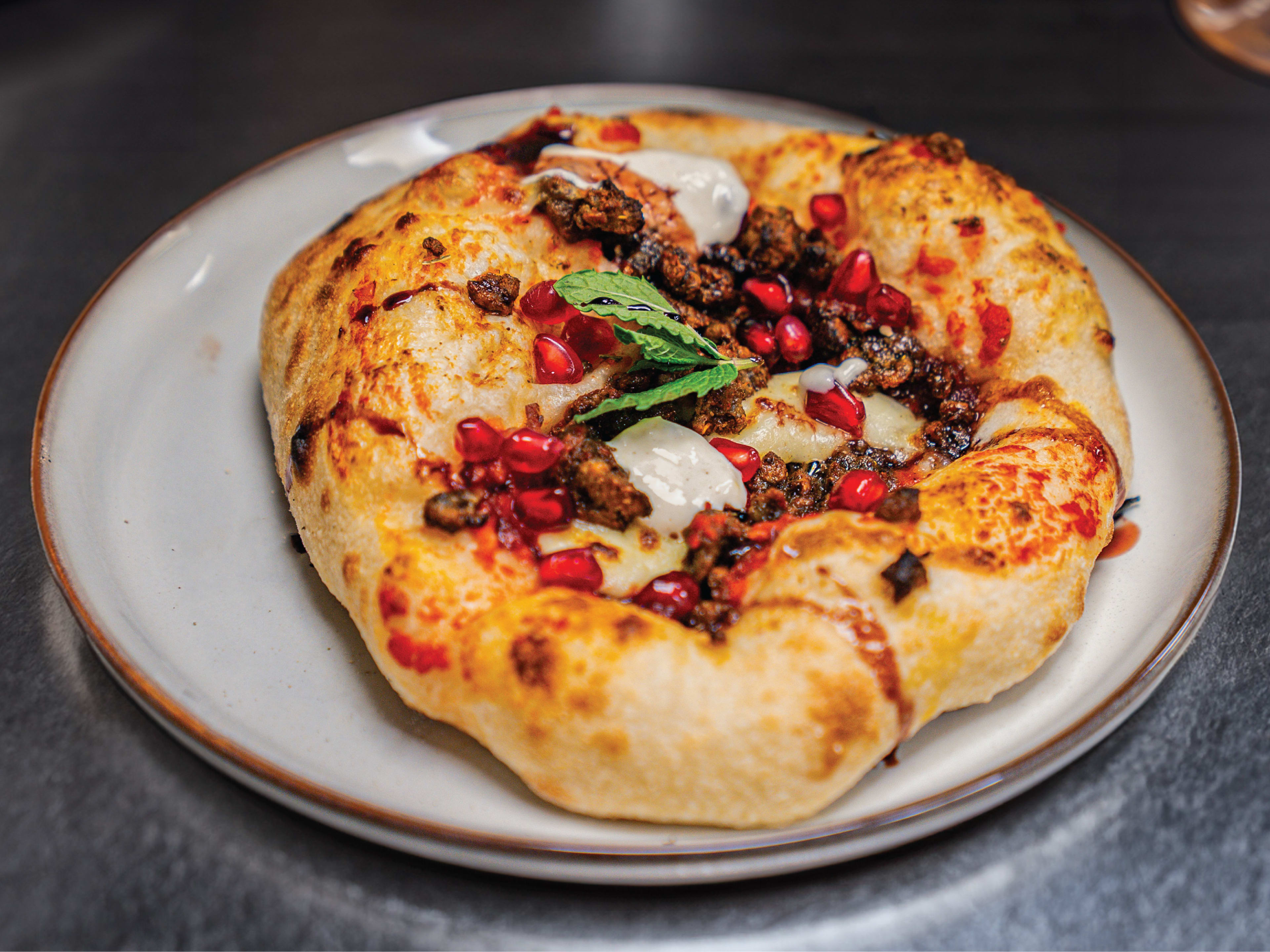 A flatbread with cheese, fried bugs, and pomegranate seeds from Yum Bug.