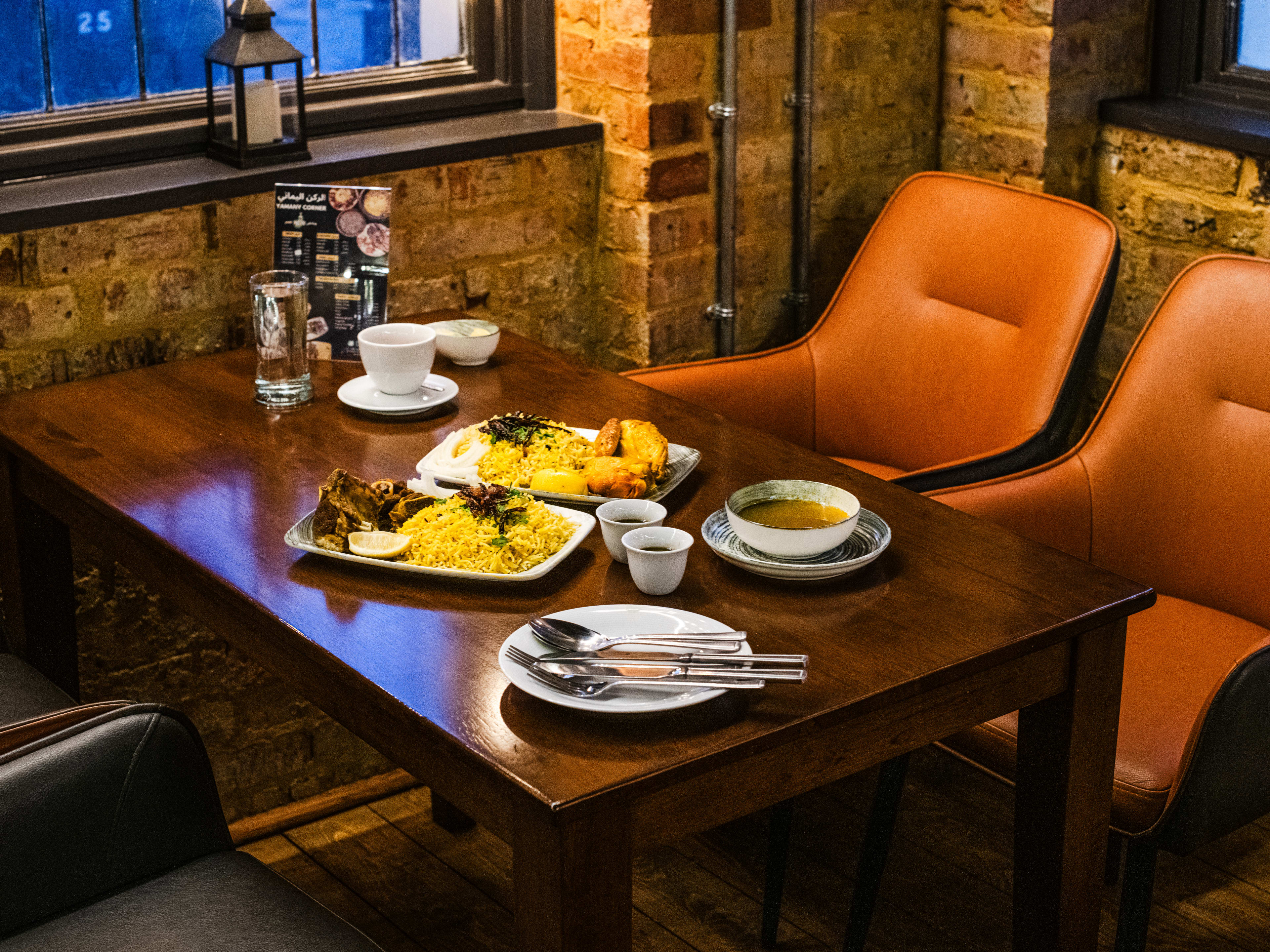 Spread of Yemeni dishes on a brown wood table.