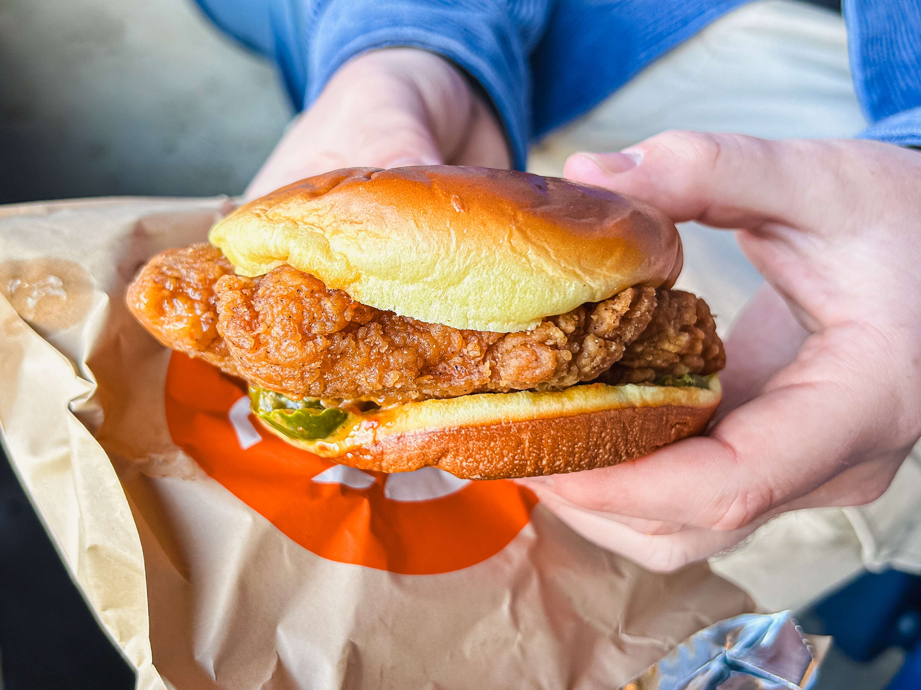 a spicy chicken sandwich with a pickle peaking out of the bottom bun