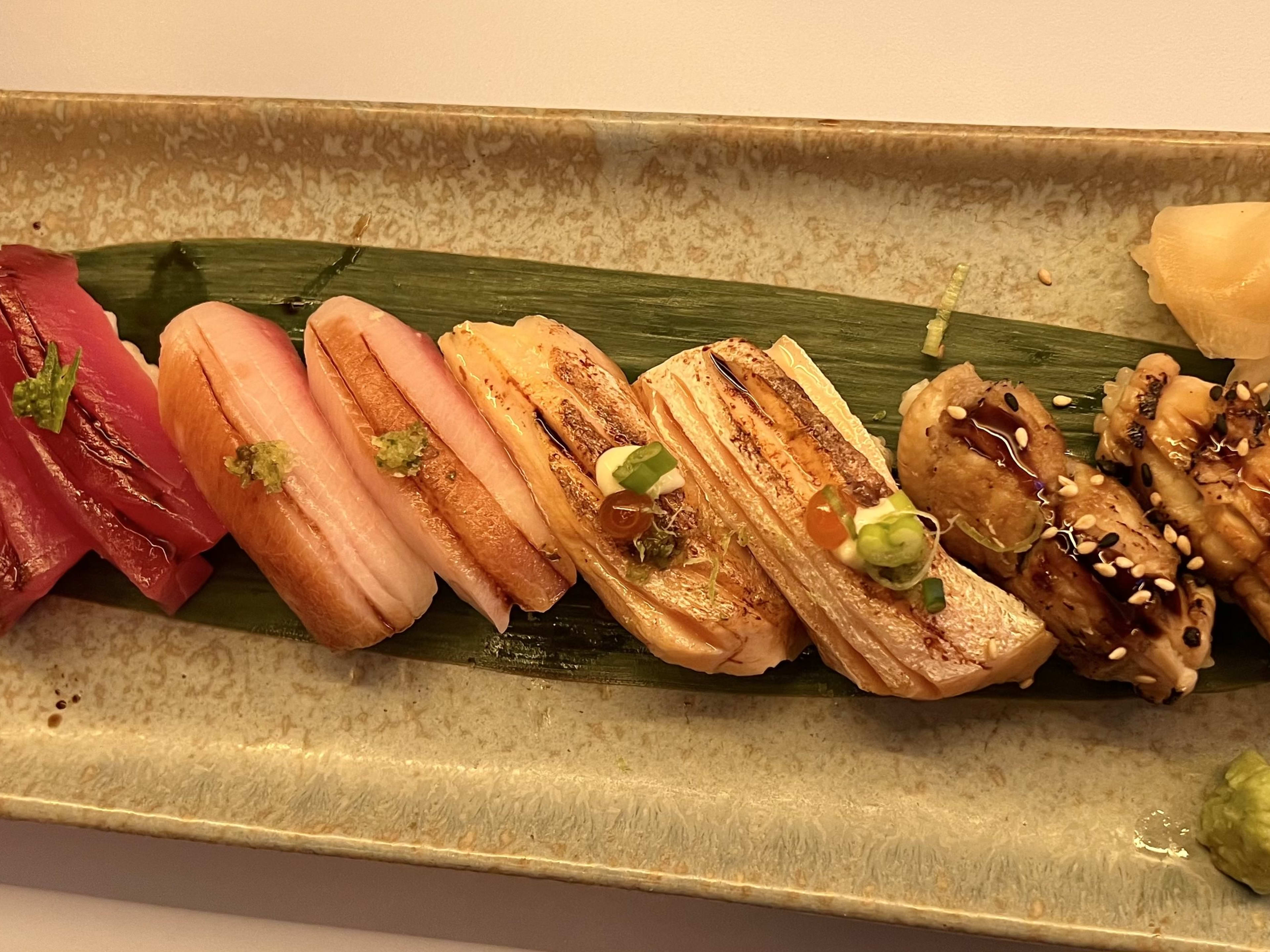 A plate of nigiri sitting on a leaf.