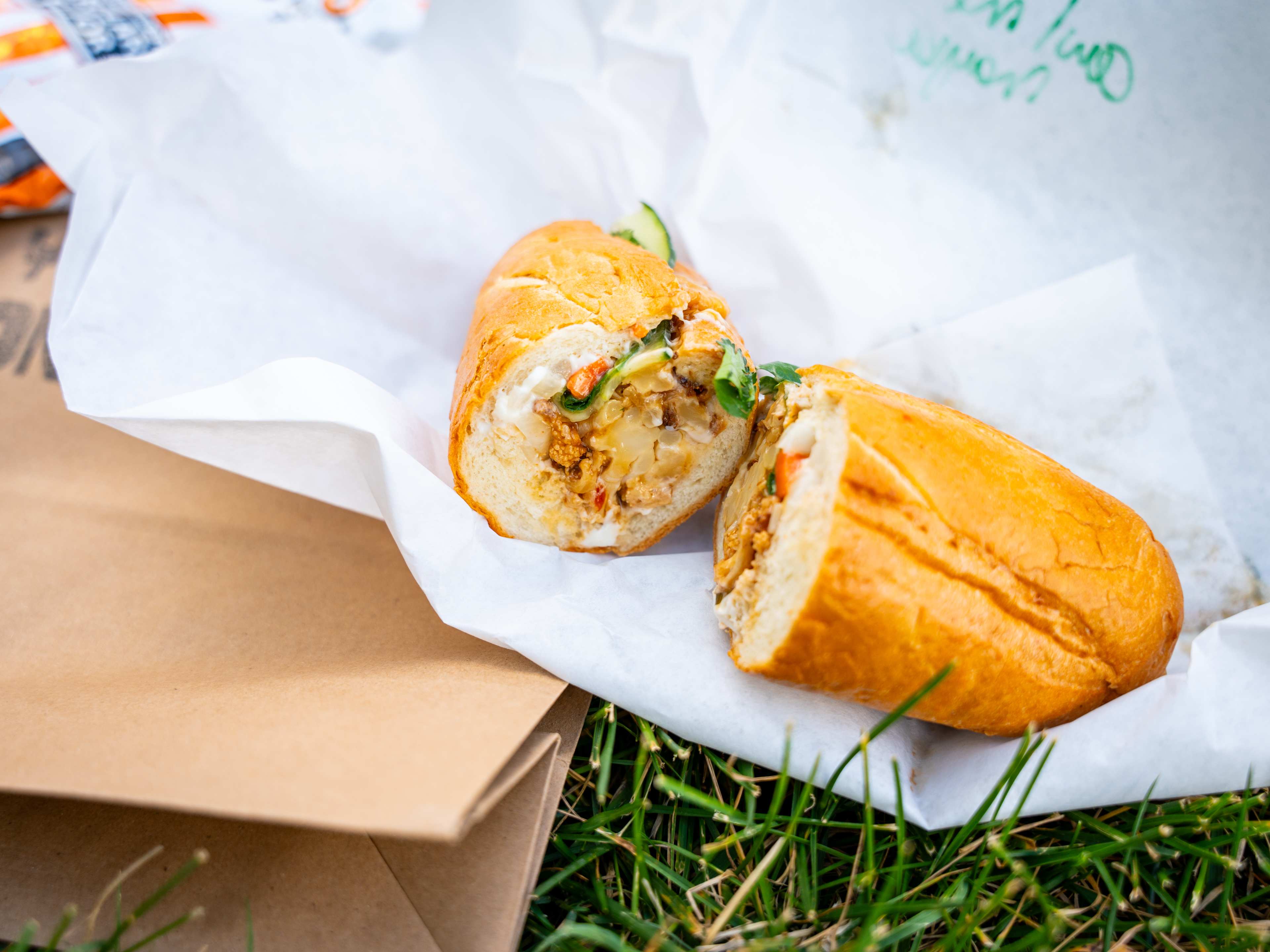 banh mi cut in half to show filling on grass