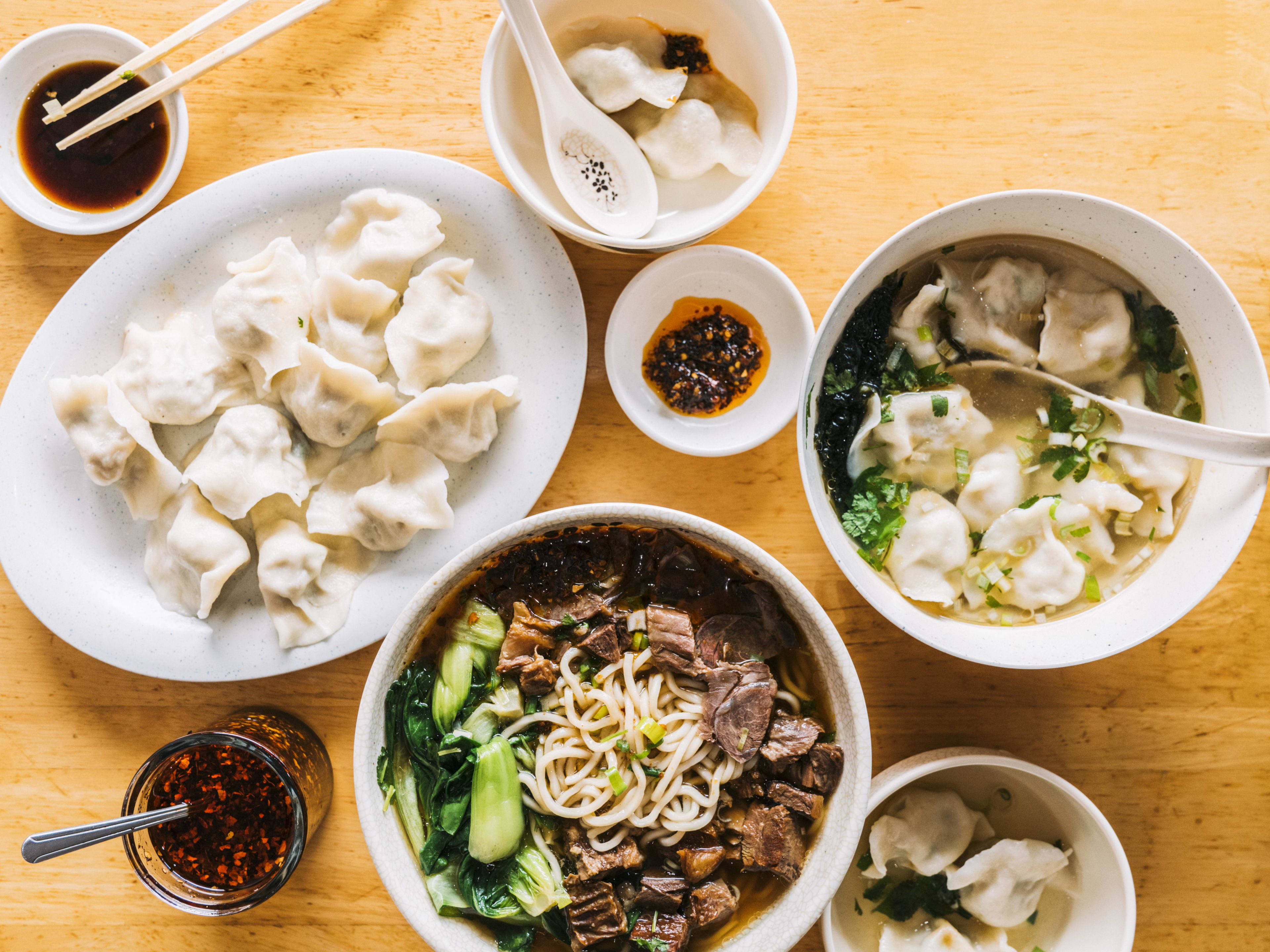 A spread of noodle soup, dumplings, and chili oil at Yuanbao Jiaozi