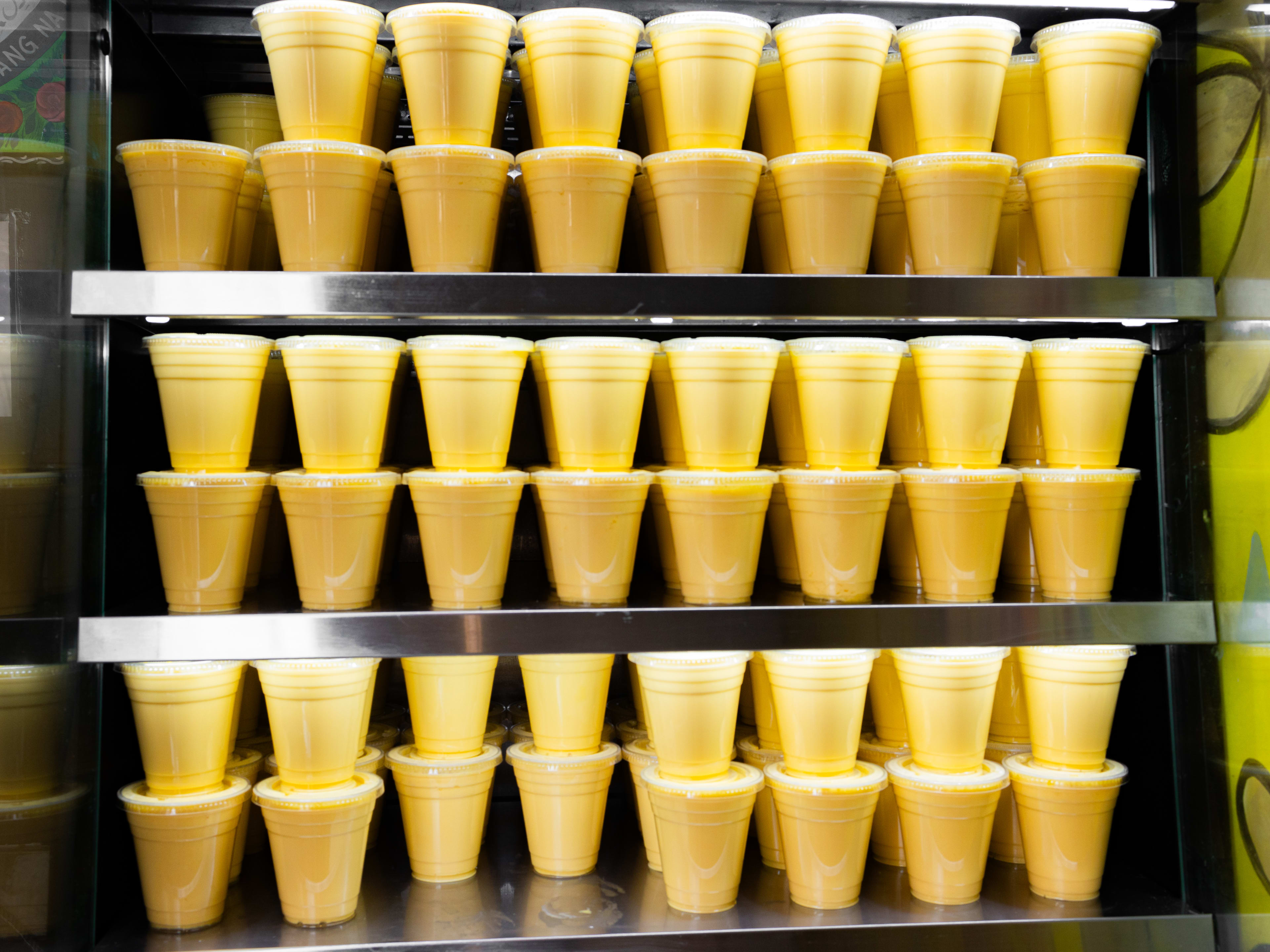 fridge full of mango lassis in disposable cups