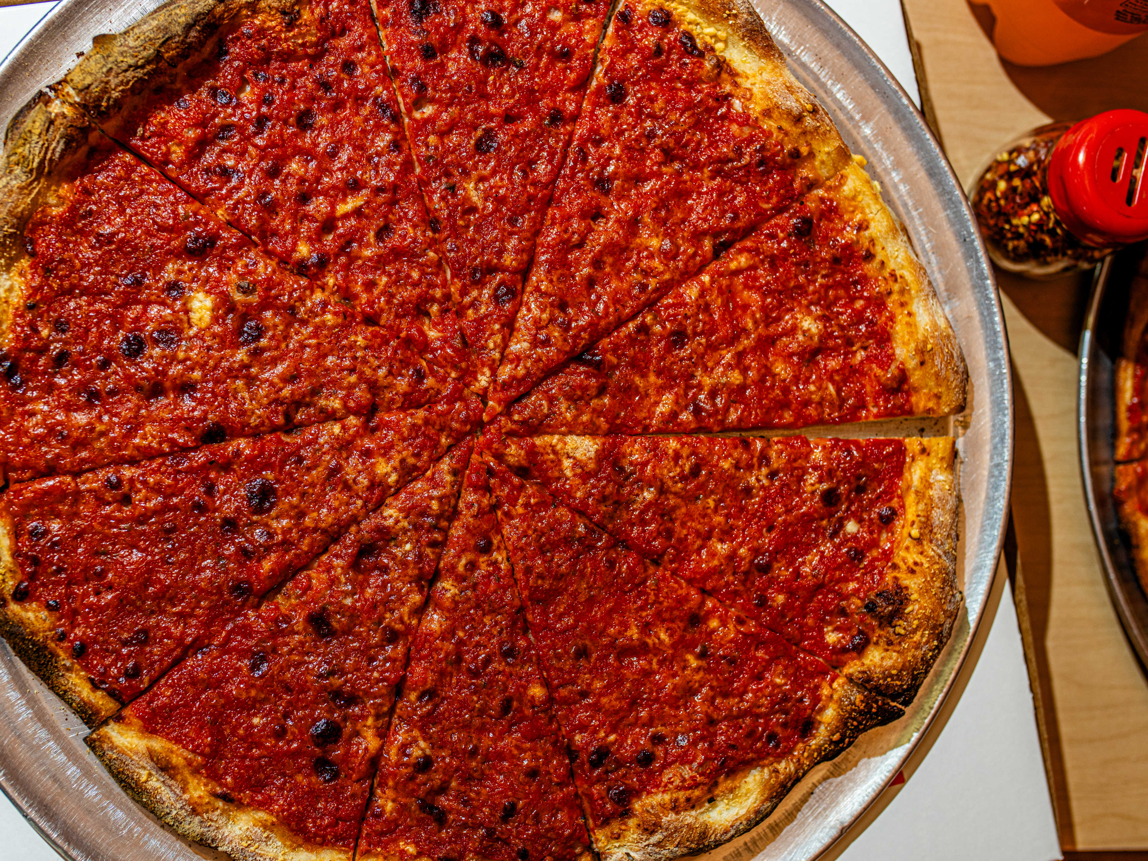 A red pizza pie on a wooden table