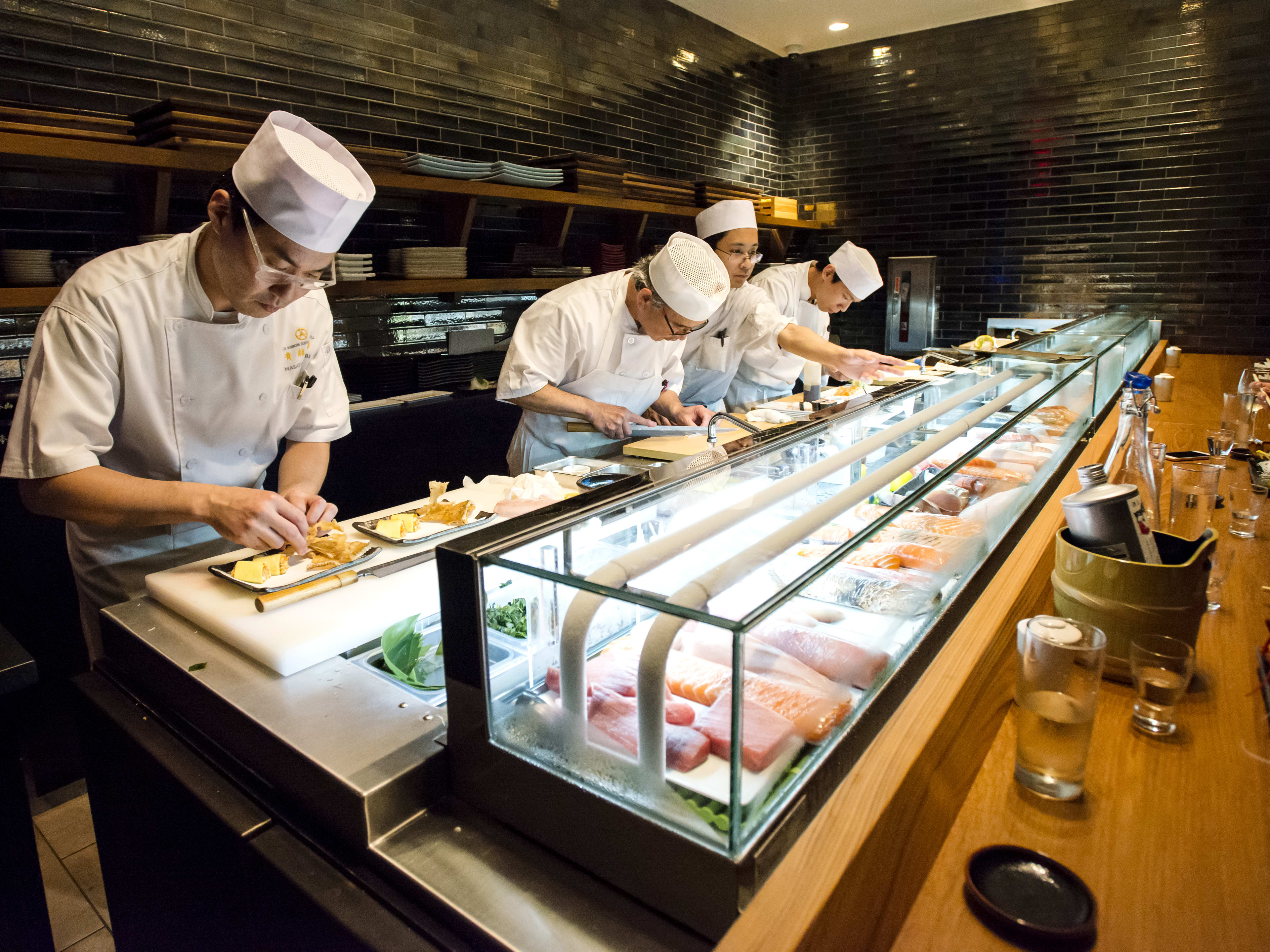 chefs behind a sushi counter making sushi