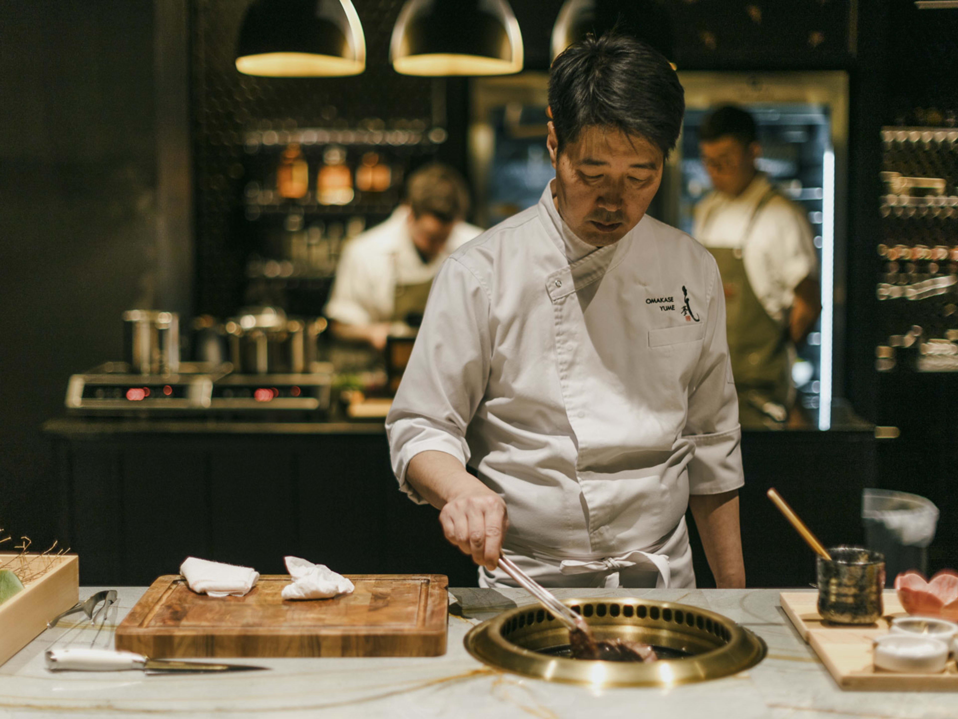 Chef cooking over a countertop grill.