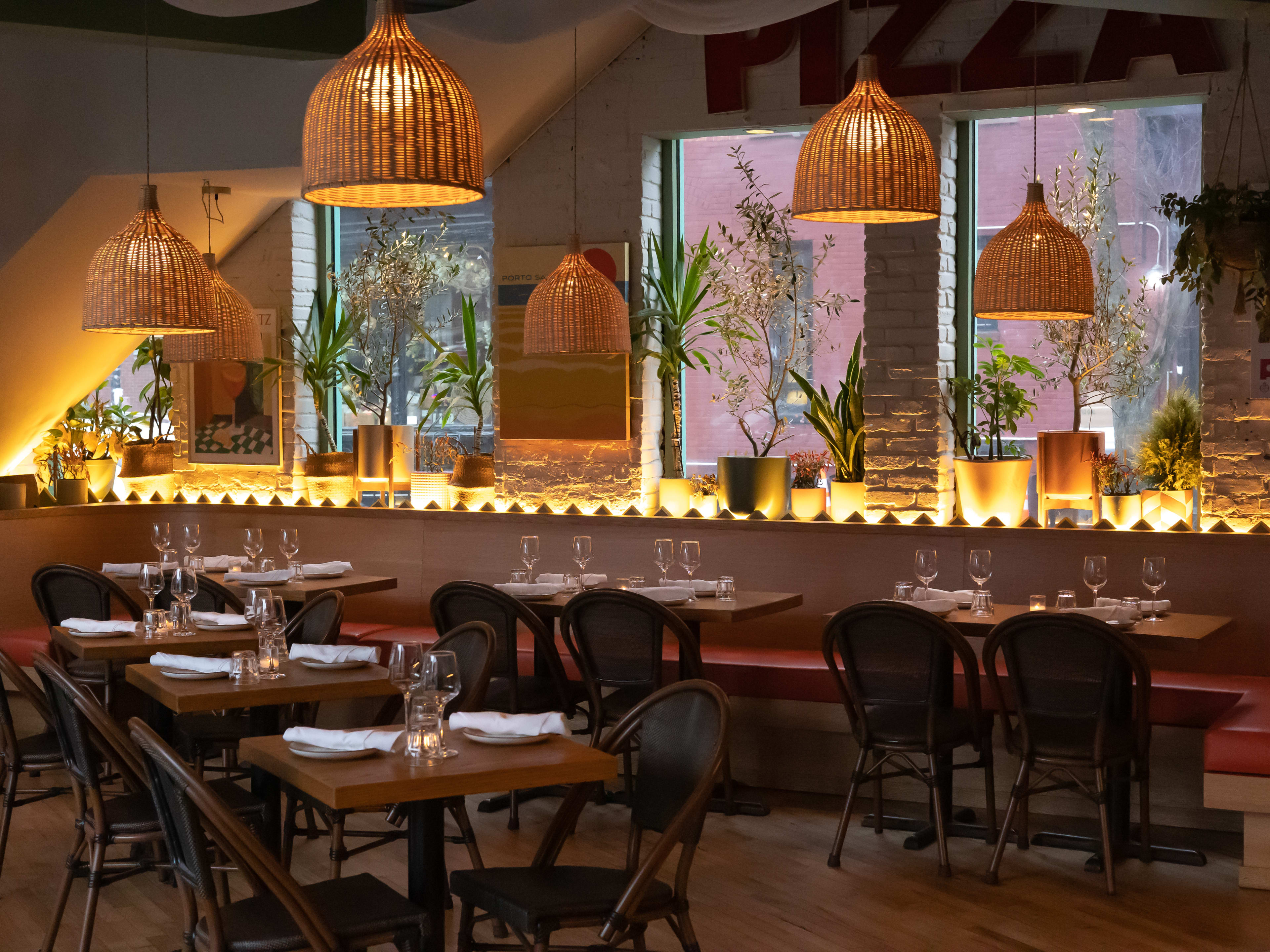 A dim restaurant interior with basket light fixtures and potted plants.