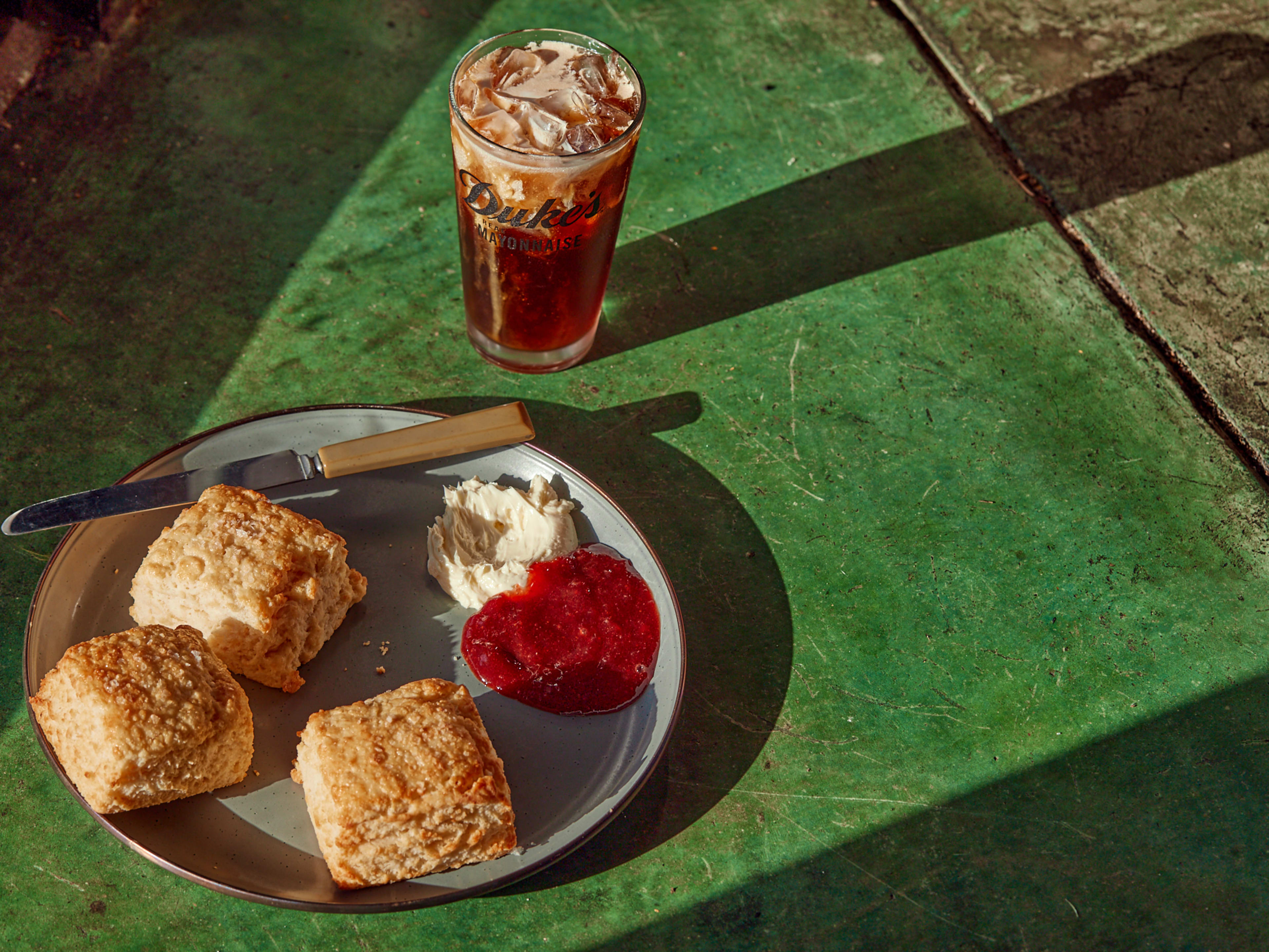 Biscuits with cream and jam on green table at Molly's Rise & Shine