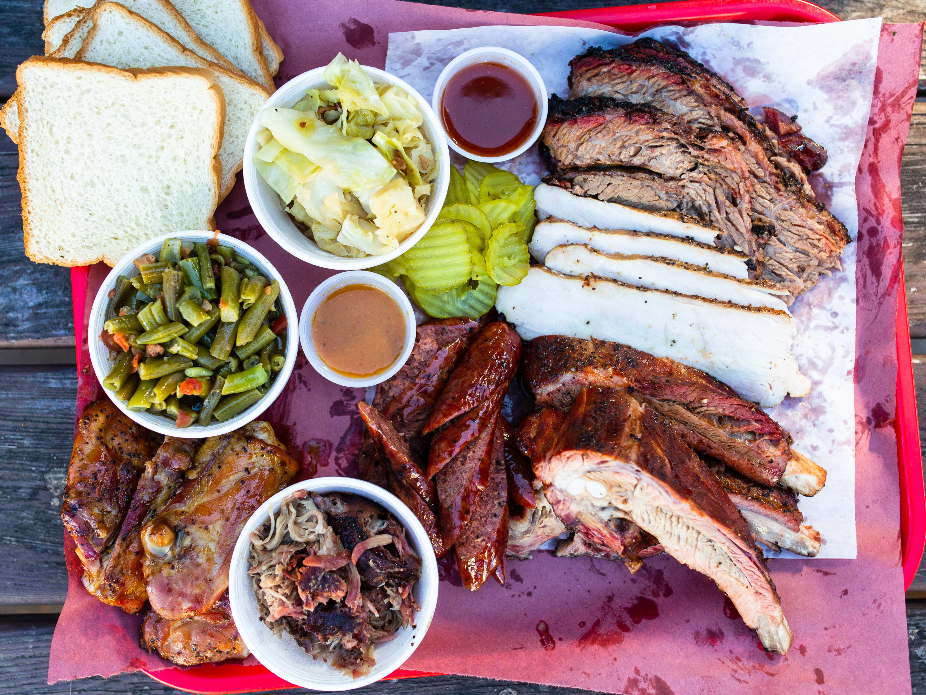 A spread of meats and sides on a red lunch tray.