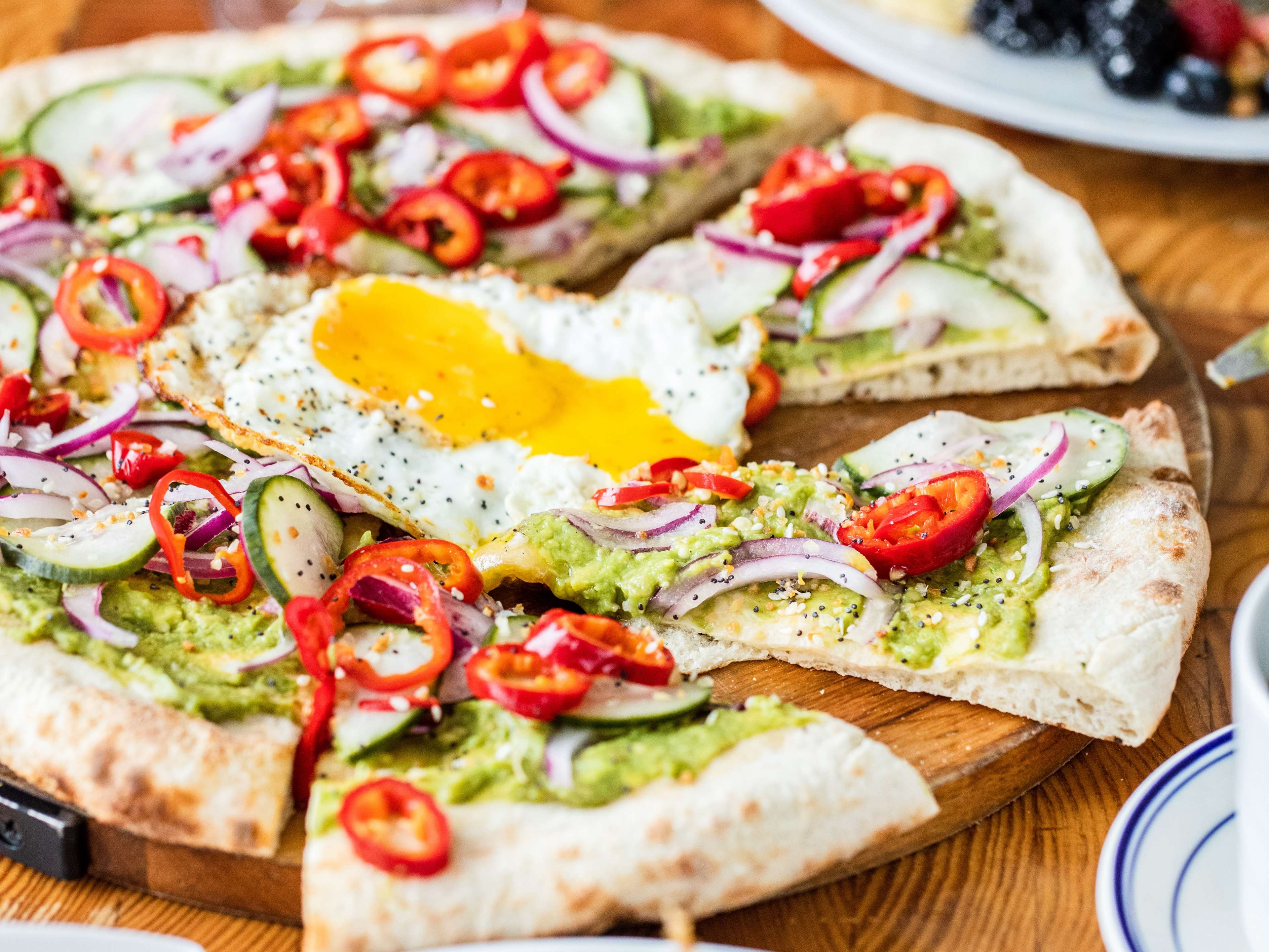 flatbread pizza covered in sliced peppers and a fried egg