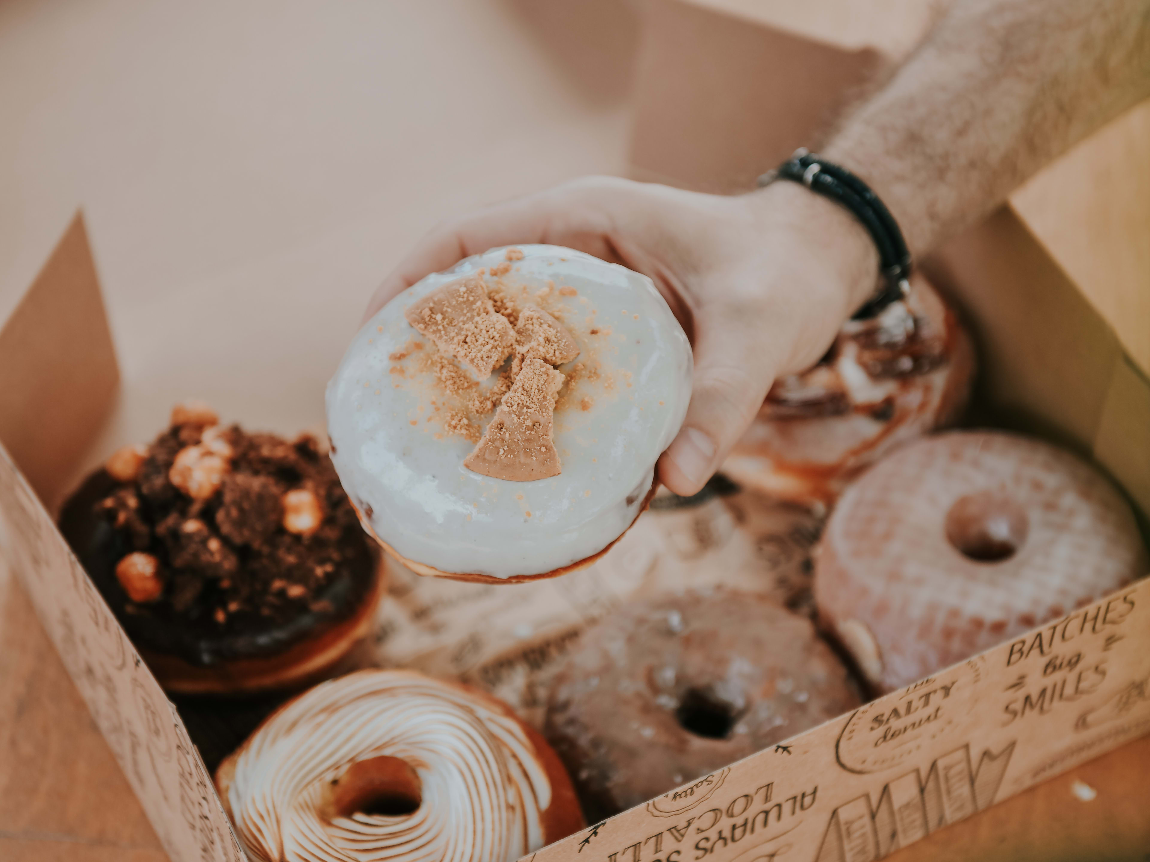 hand reaching into a box of donuts