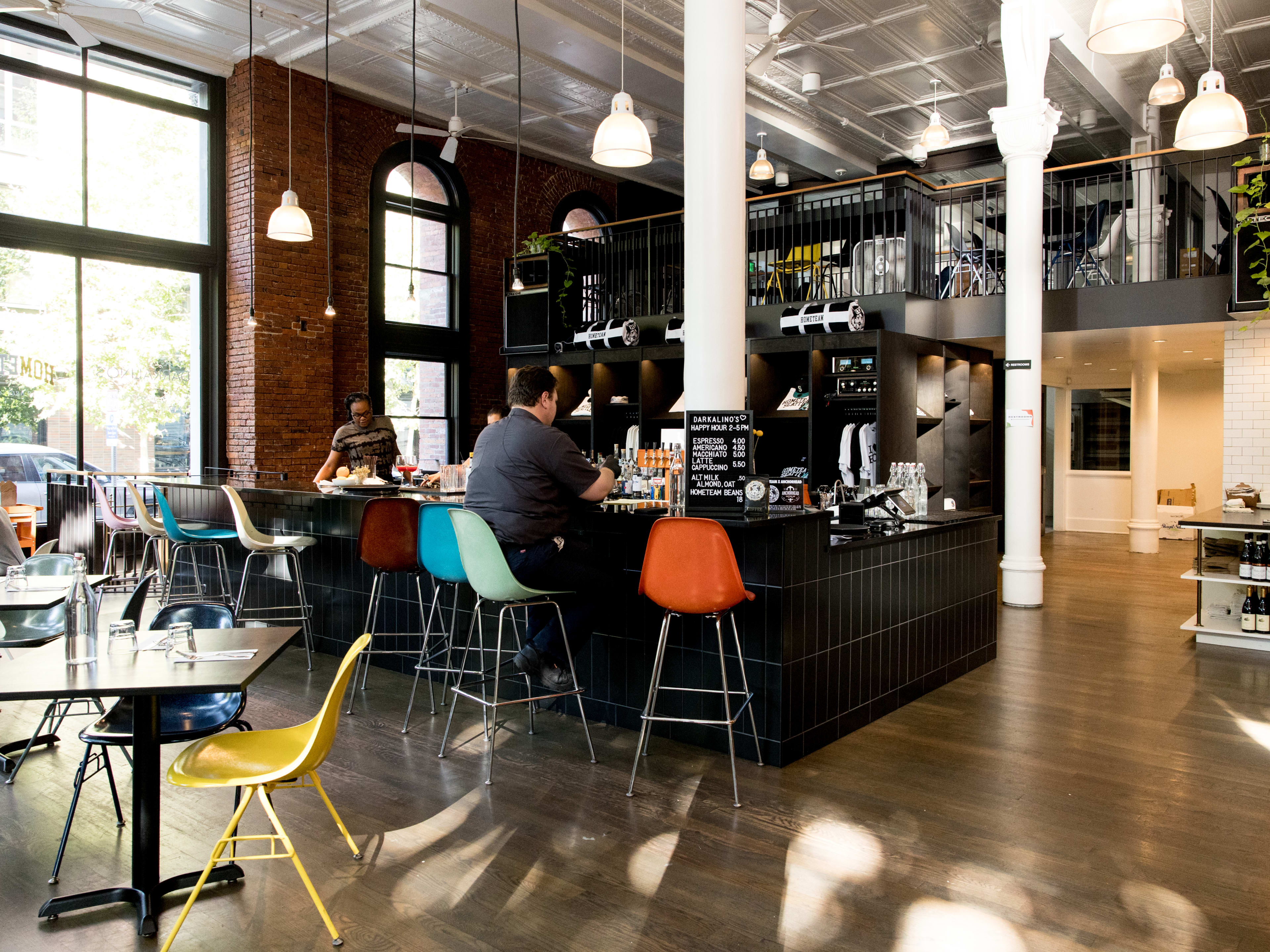 dining room with a bar in the middle, loft seating upstairs, and small tables on the left