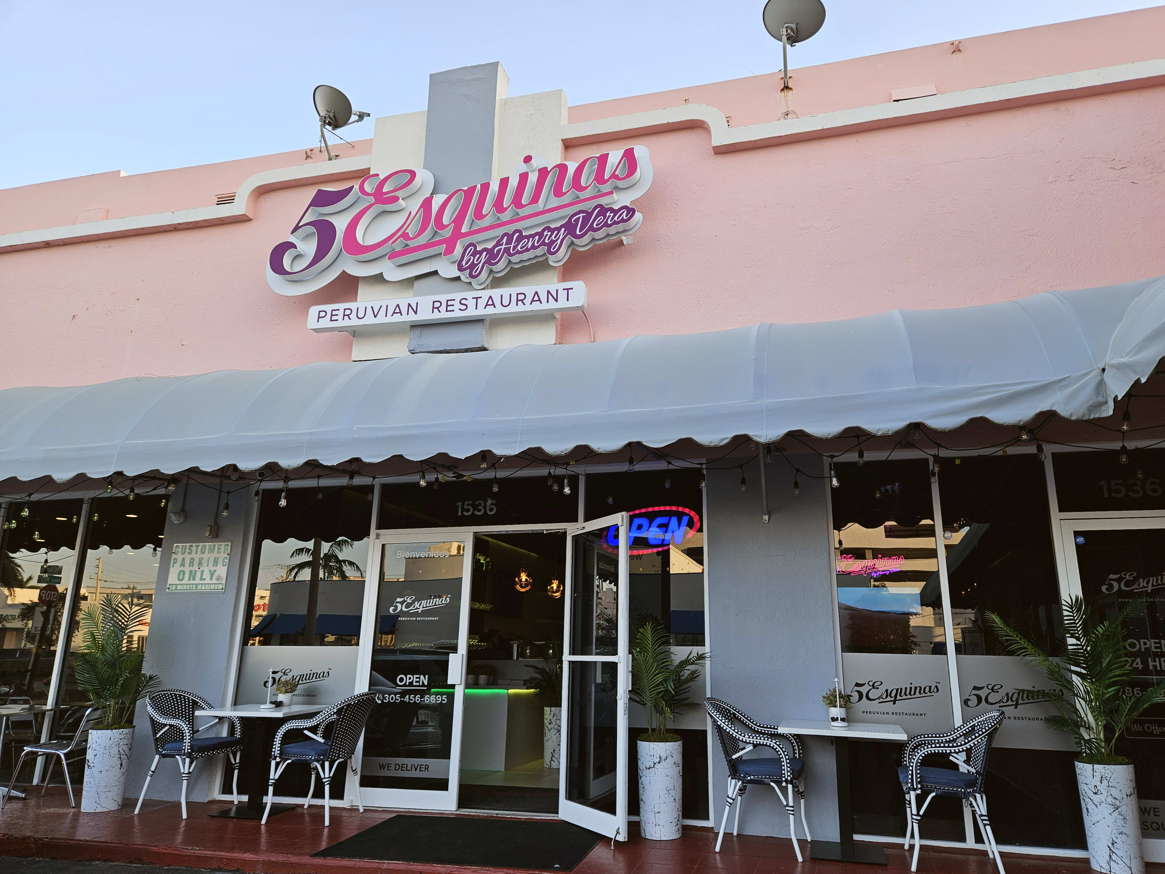 exterior of light pink restaurant with 3 two-person dining tables