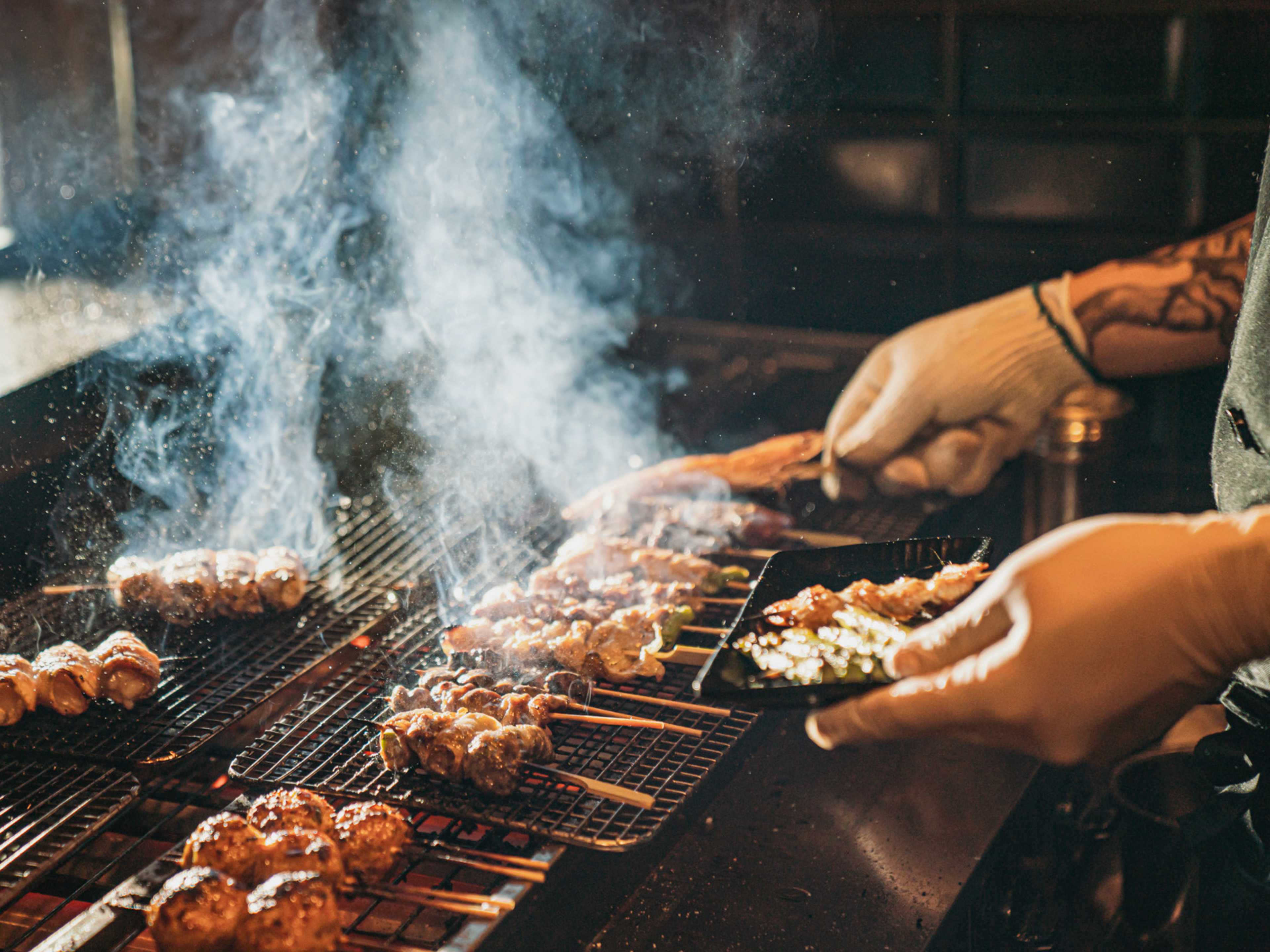 someone working a yakitori grill with lots of skewers on it