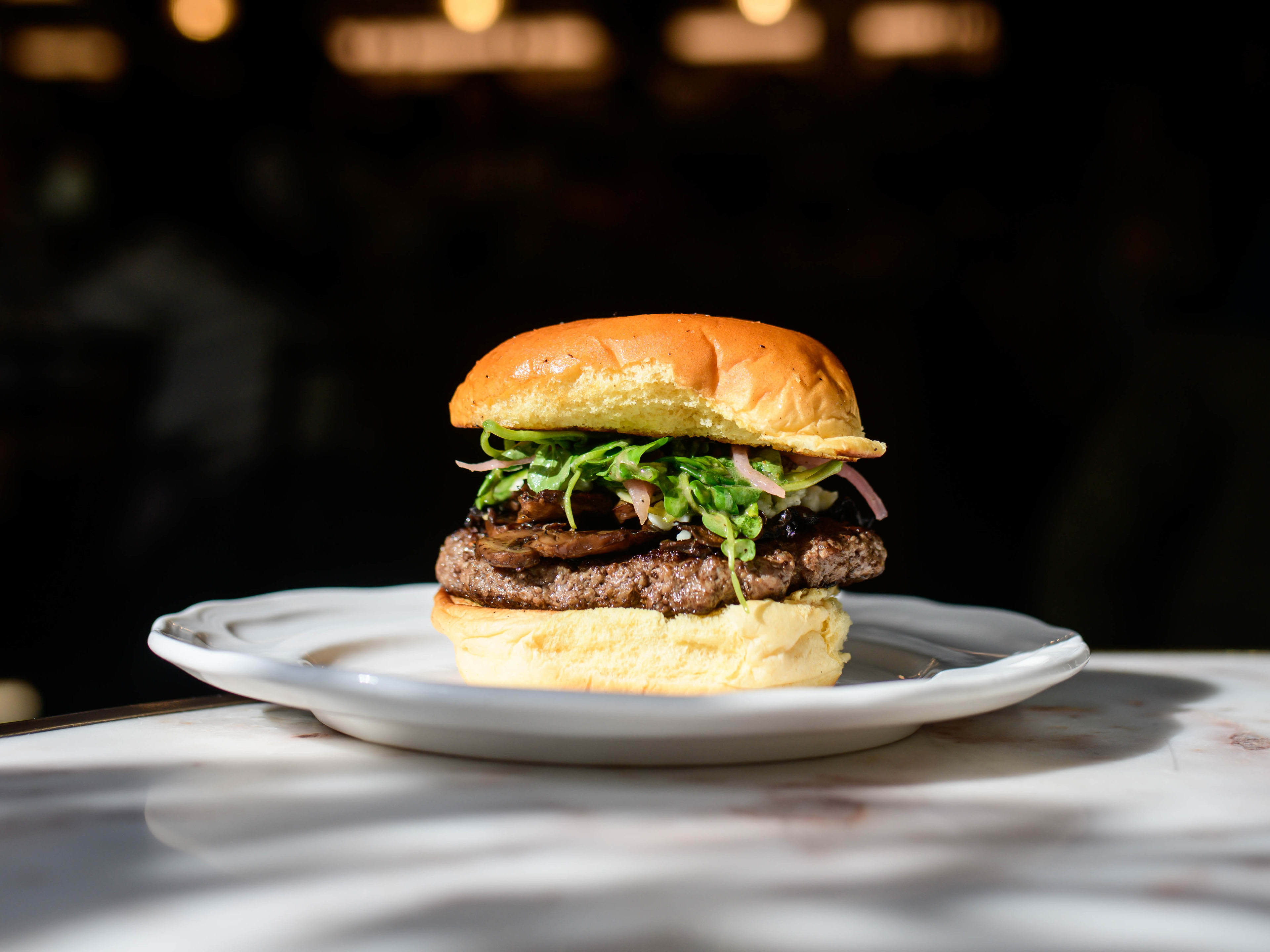 burger with patty greens shallots on a potato bun