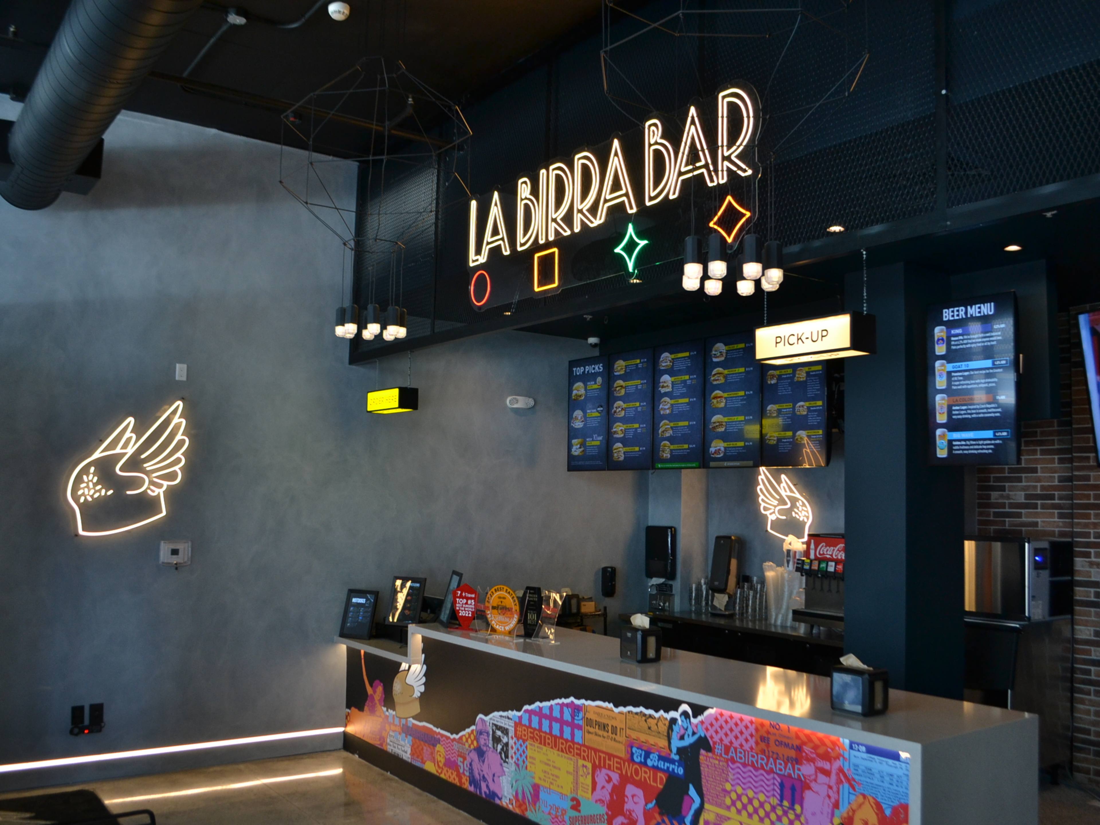 interior of counter at birra bar with neon signs and ordering screen