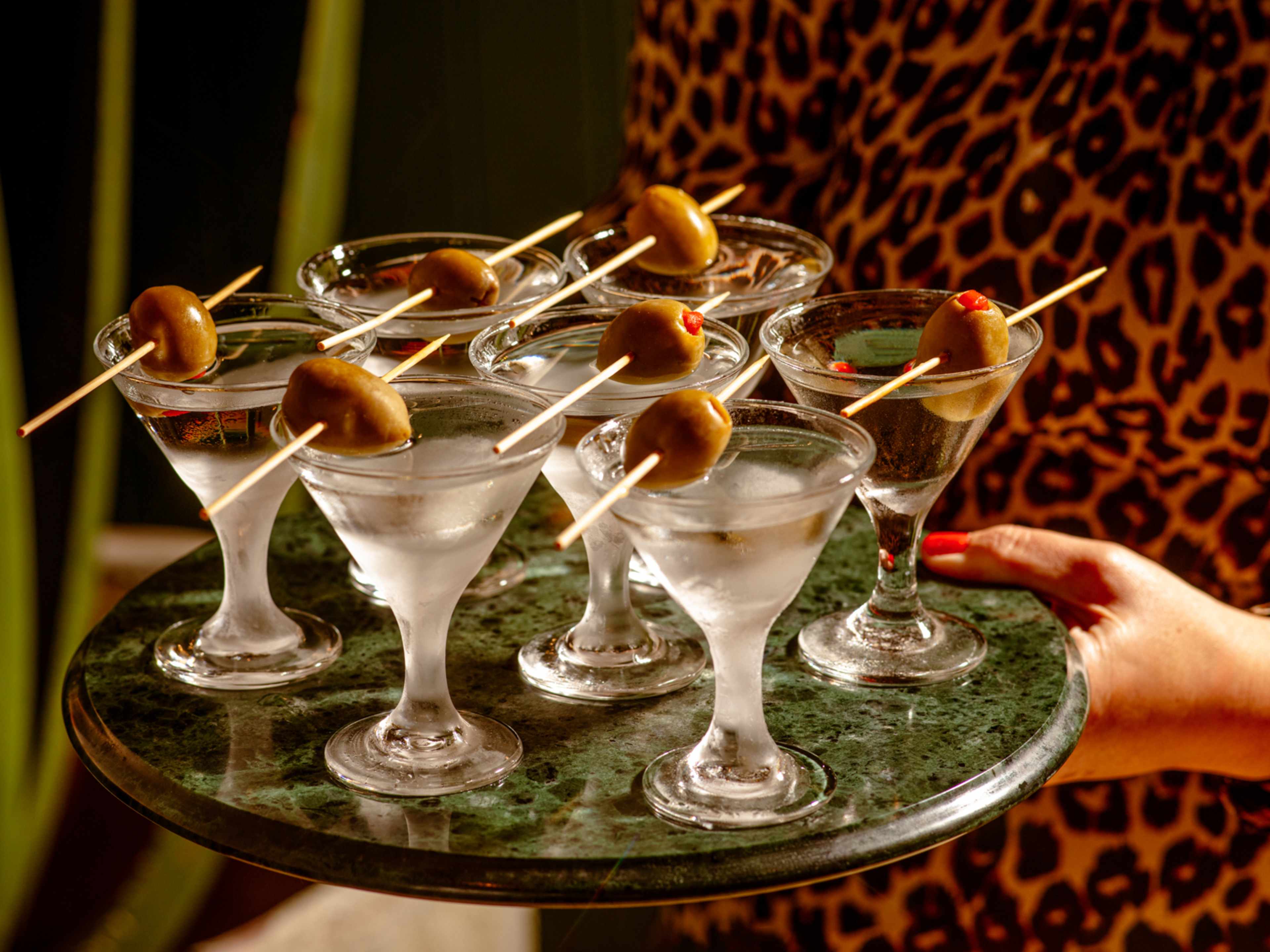 person holding tray of martinis with olives