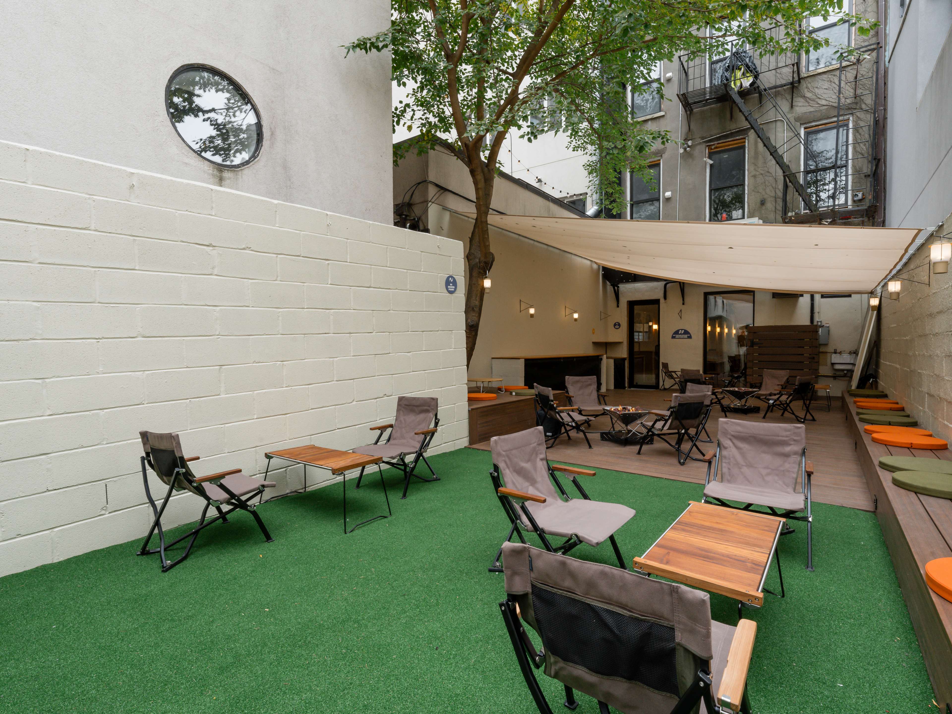 the backyard at taku sando with tables, chairs, and a canopy