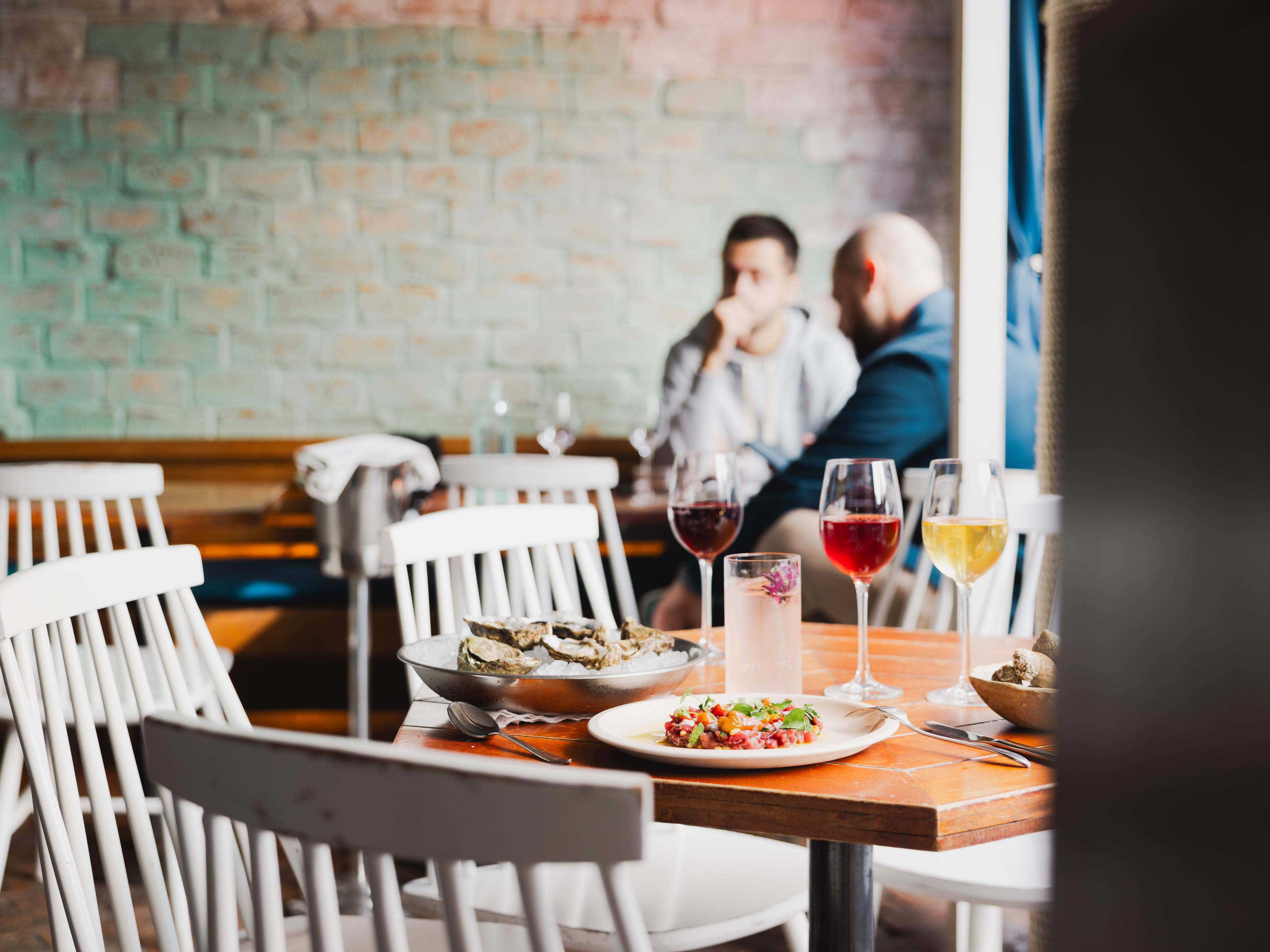 Spread of food and colorful natural wines on wooden table at Le Mary Celeste